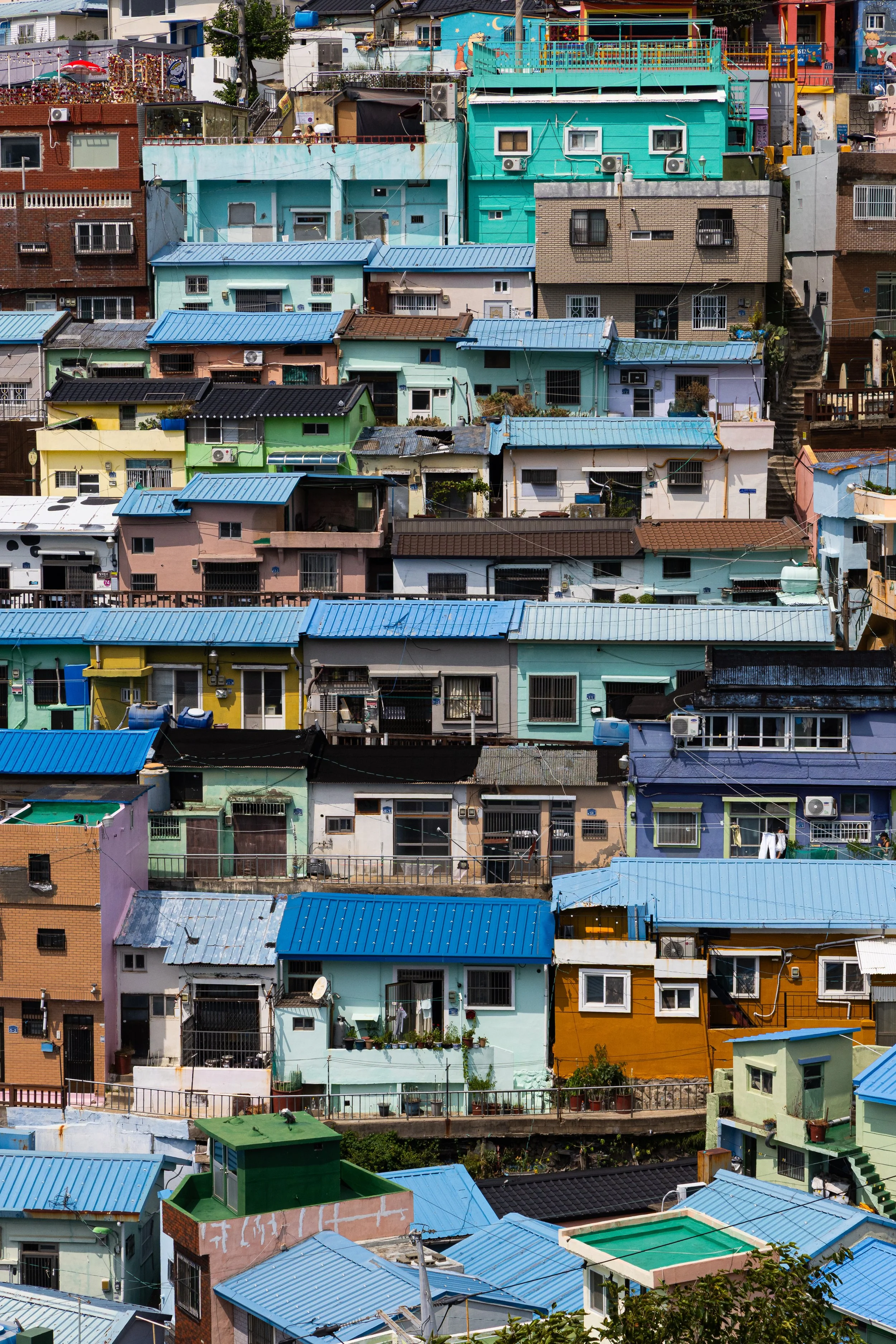 Colorful hillside residential buildings with blue and other colored roofs, closely packed together.