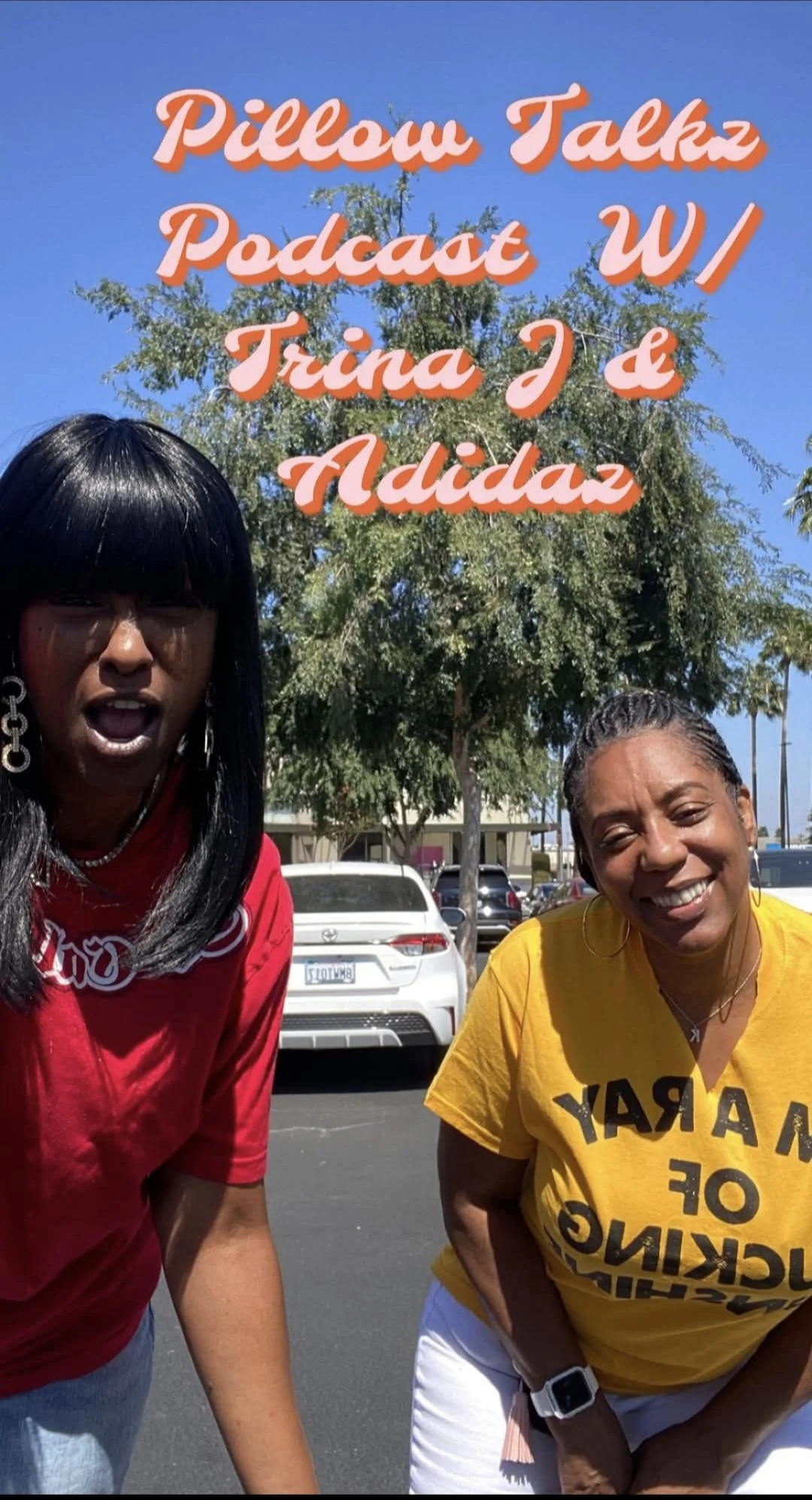 Two women standing outdoors in a parking lot with trees and cars behind them. One woman is wearing a red shirt and has long black hair, and the other is wearing a yellow shirt with black text and has short braided hair. The image has text overlay that reads, 'Pillow Talkz Podcast W/ Trina J & Adidaz.'