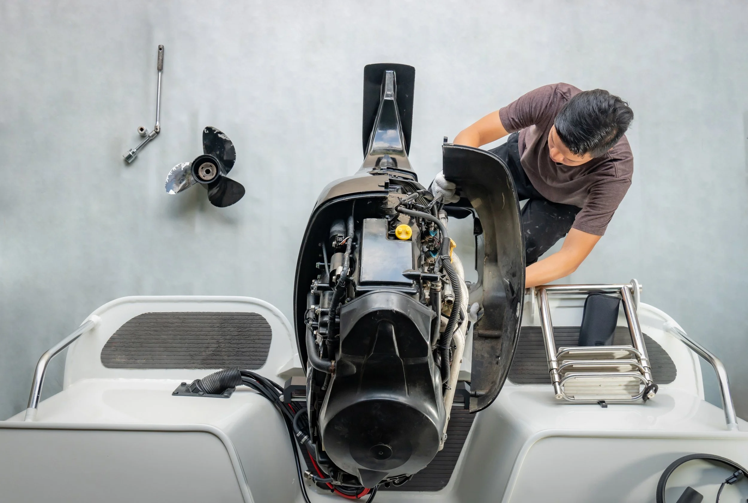 A man working on a boat engine in a workspace.