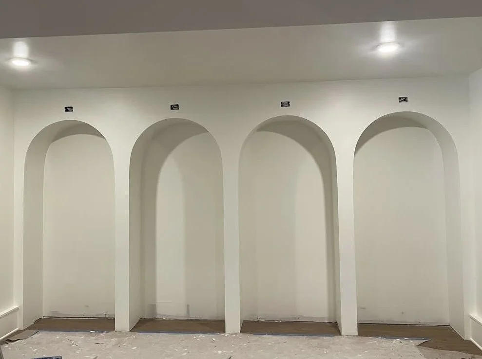 Interior wall with four arched alcoves, each marked with a number, under ceiling lights.