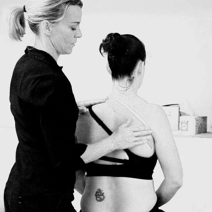 A woman receiving a massage or physiotherapy on her back from a practitioner in a clinical setting.