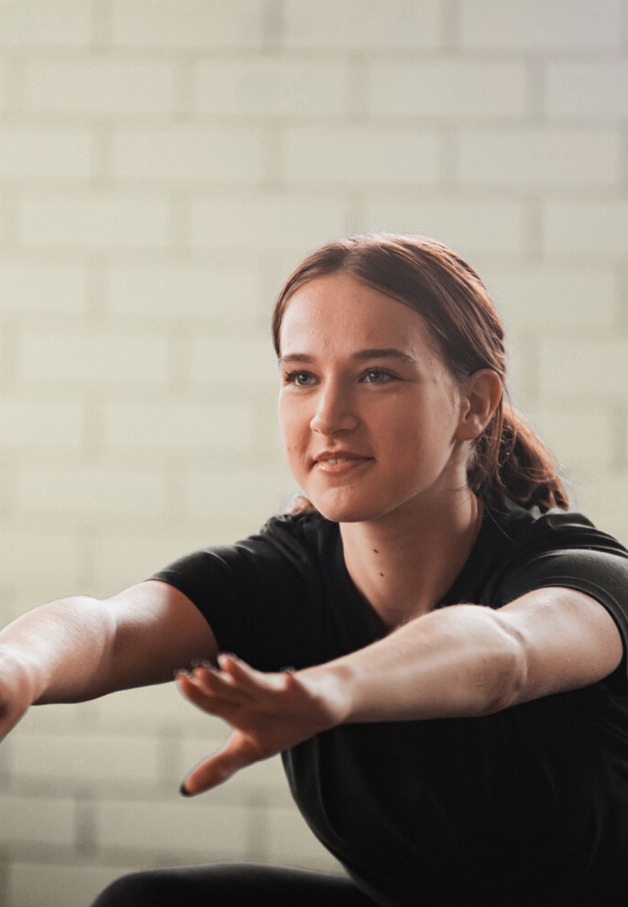 A woman doing a stretching exercise, extending her arms forward with a peaceful expression