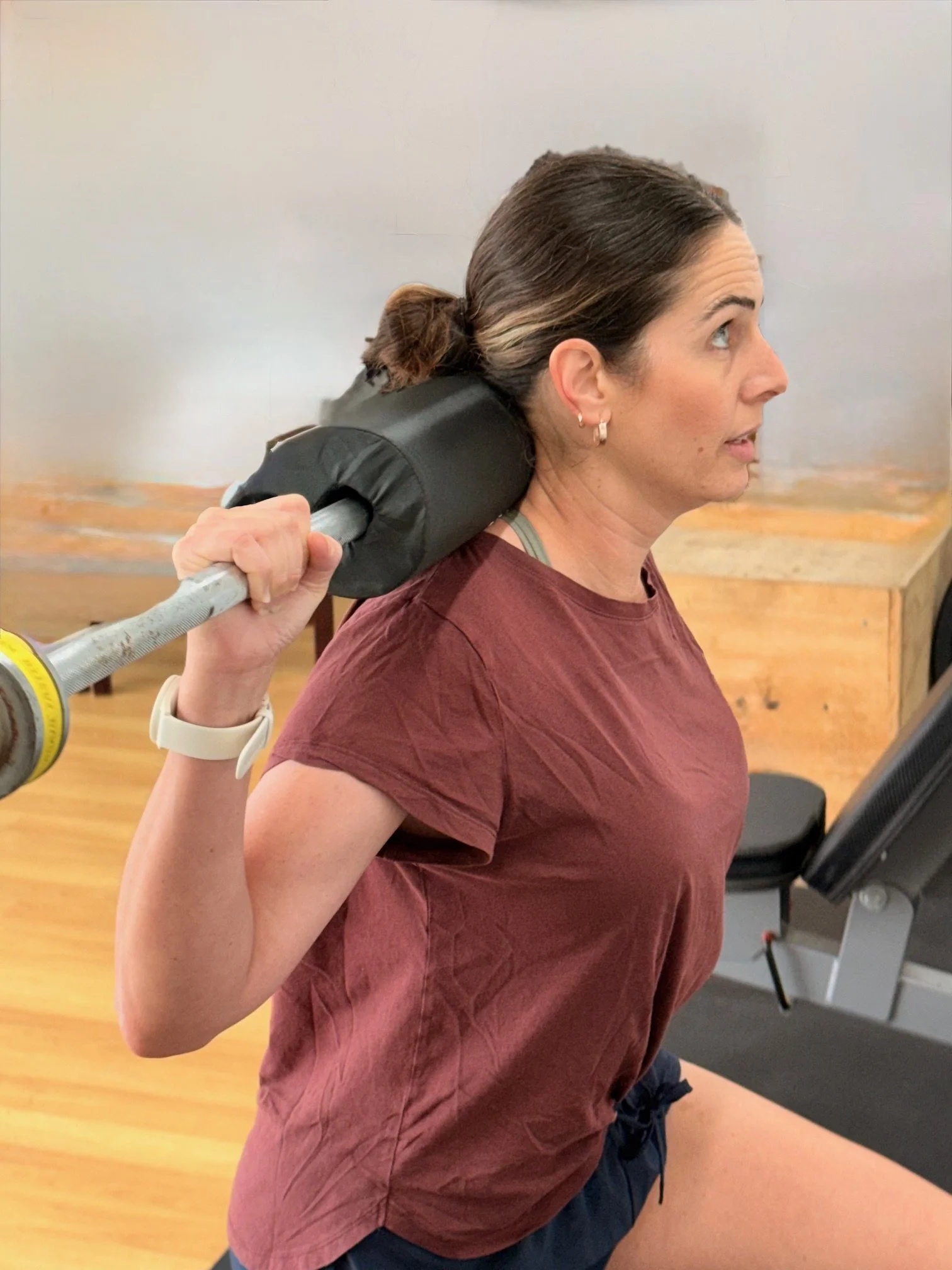 Woman doing a shoulder exercise with a barbell in gym.