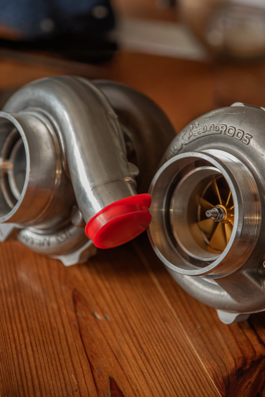Close-up of two turbochargers placed next to each other on a wooden surface.