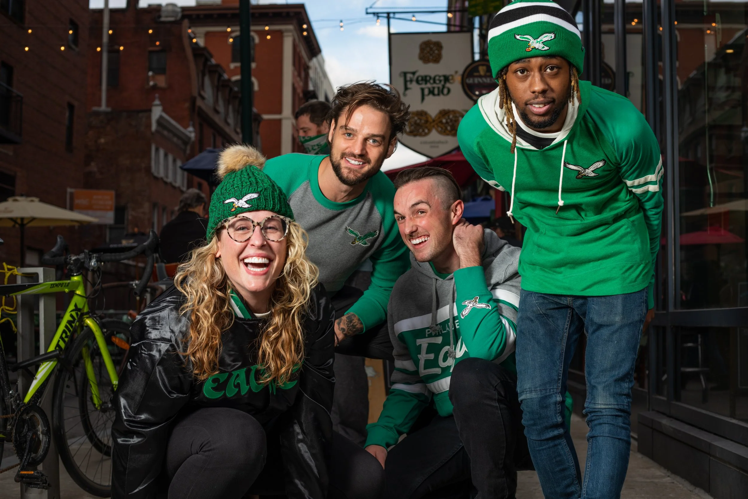Group of friends wearing Philadelphia Eagles gear smiling on a city street.
