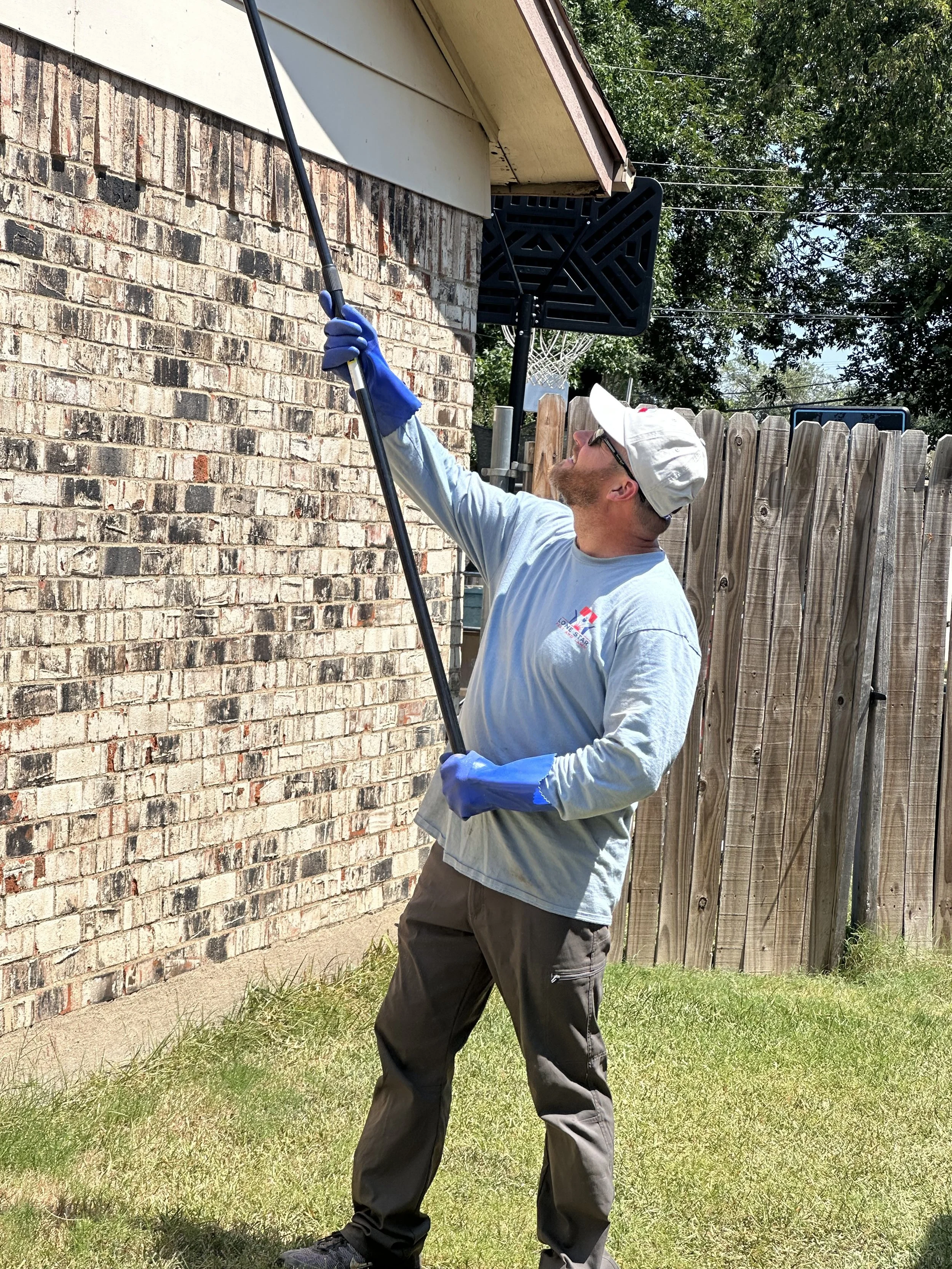 Lone Star Pest and Lawn technician performing exterior pest control treatment on brick home in North Texas