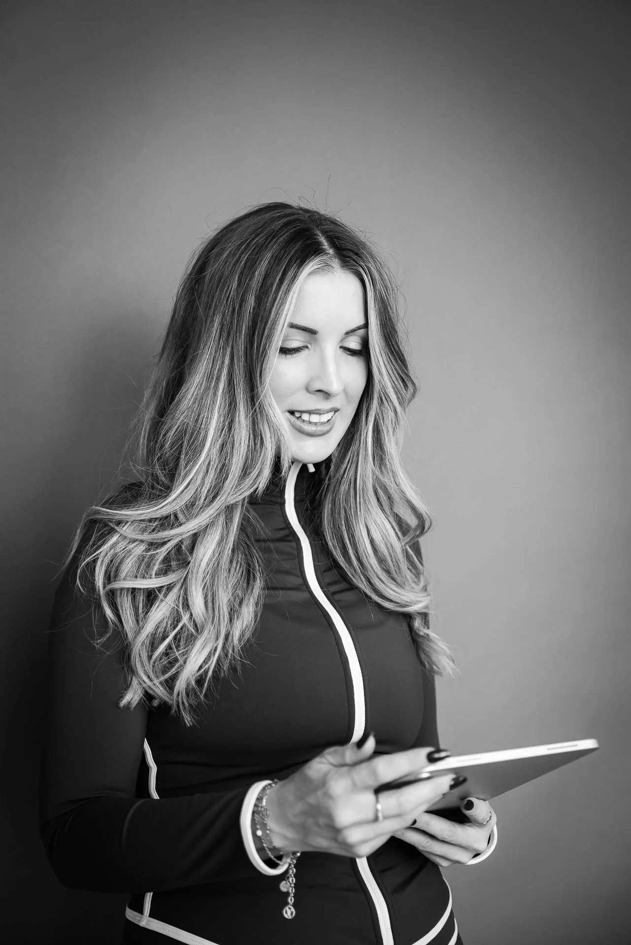Black-and-white portrait of a woman with long wavy hair holding an iPad