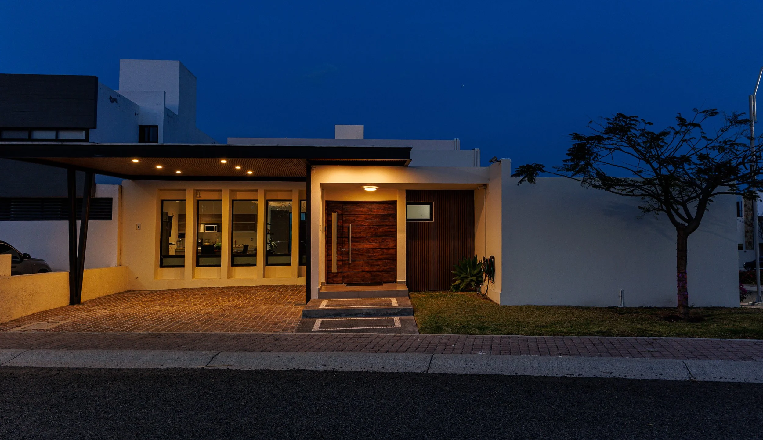 Fotografía de arquitectura residencial durante deep blue hour en Querétaro destacando fachada contemporánea con iluminación arquitectónica.