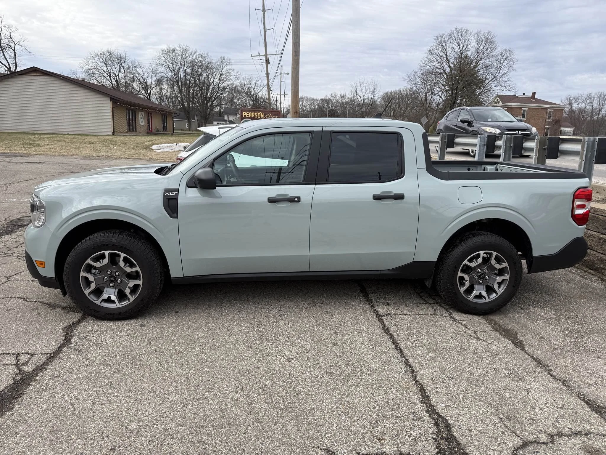 Side view of a light gray pickup truck parked on a cracked asphalt surface.