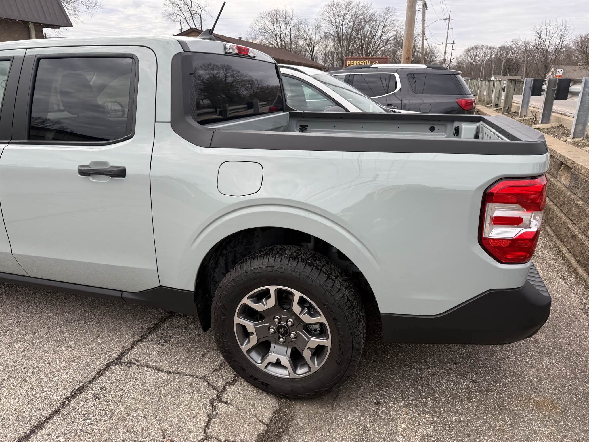 Silver pickup truck parked outdoors with a large bed and black accents, surrounded by other vehicles and utility poles.