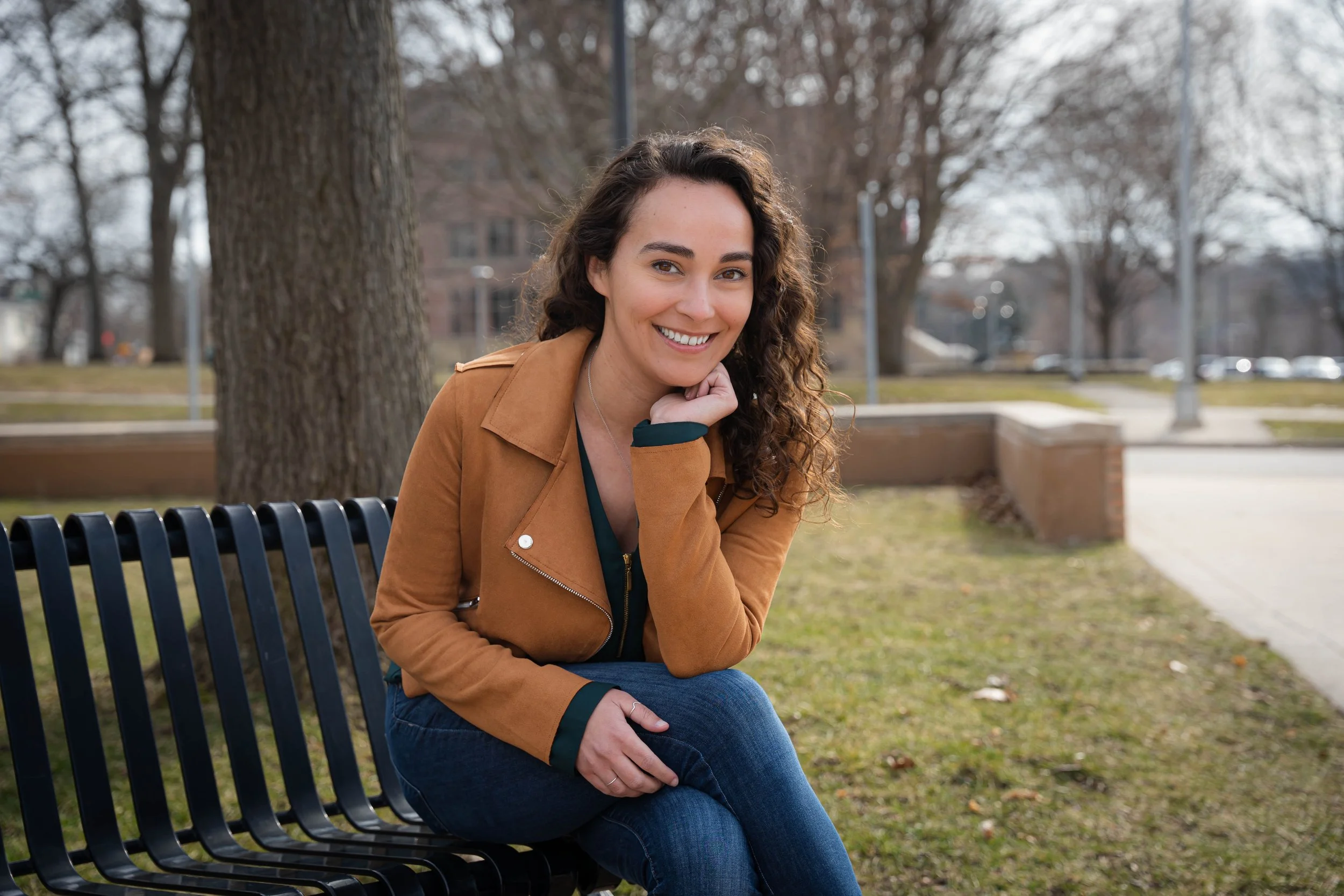 image of Kate Ford sitting on a bench in Central Park, Grand Haven MI. Photo credit: Chase Loreto