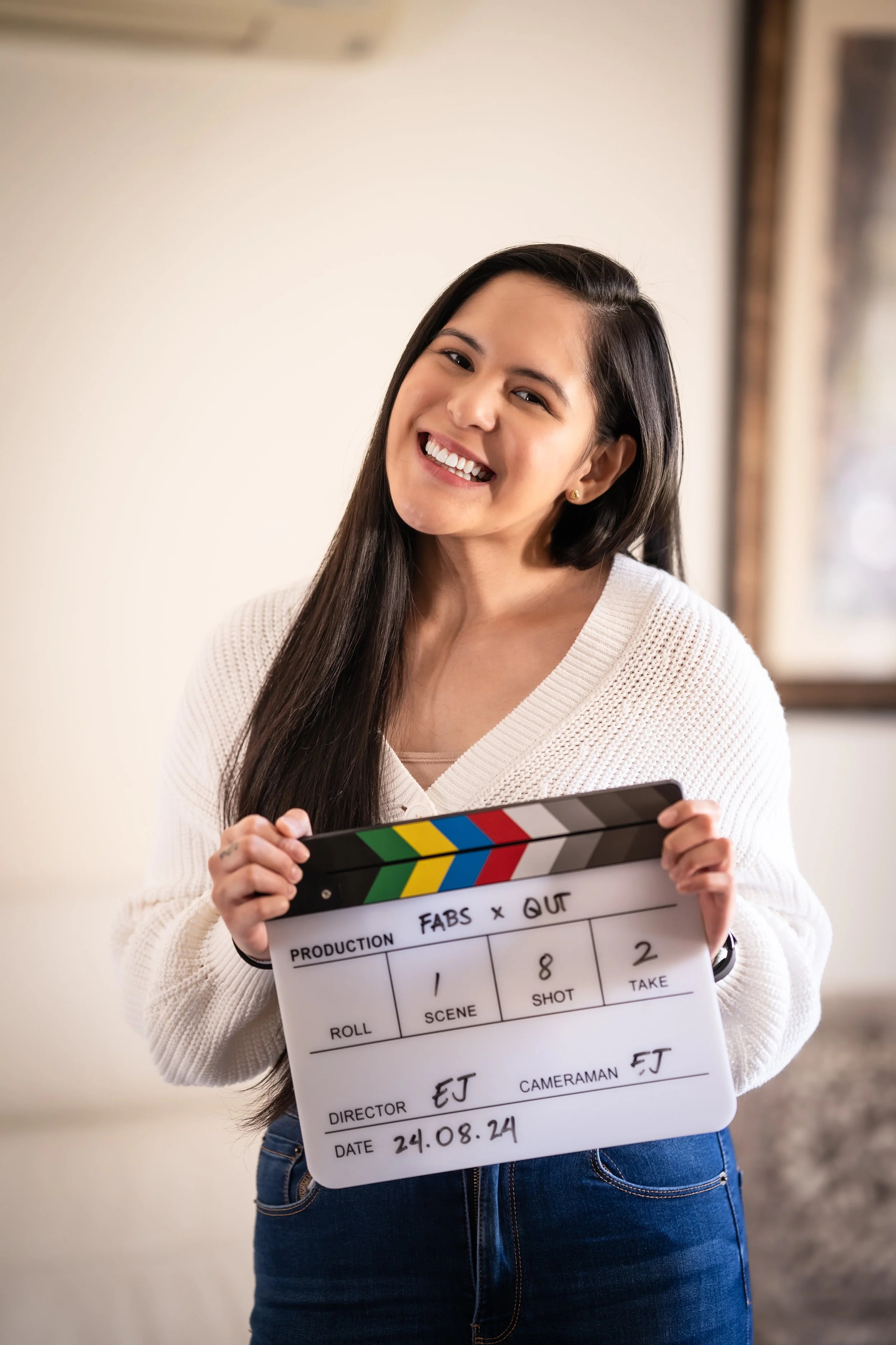 Smiling woman holding a film clapperboard for a film production shoot.