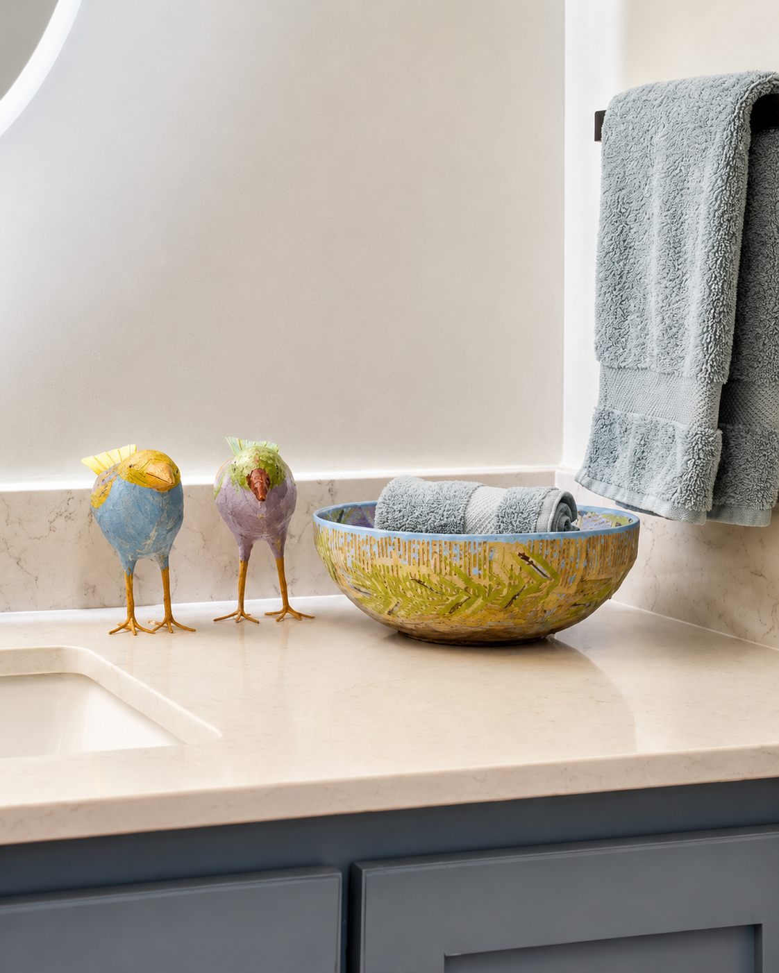 Bathroom vanity detail with decorative accessories and rolled towels in a painted basket.