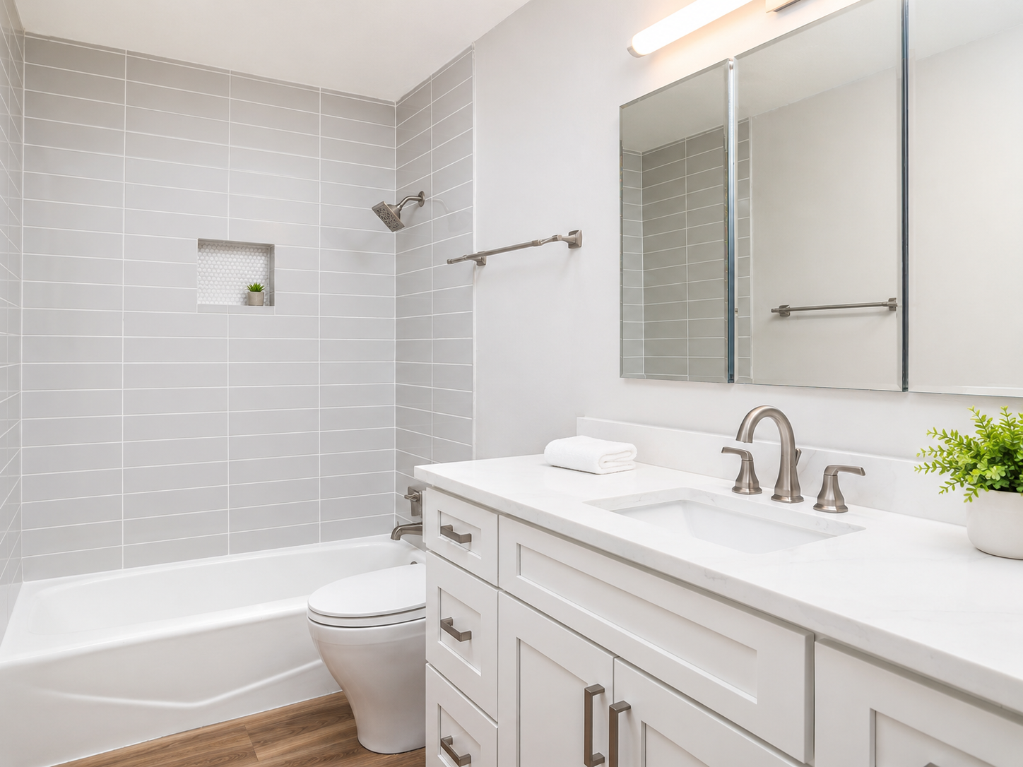 Primary bathroom with white vanity cabinetry, white quartz countertop, large neutral tile with minimal grout lines, brushed nickel fixtures, and extra large mirrored medicine cabinet.