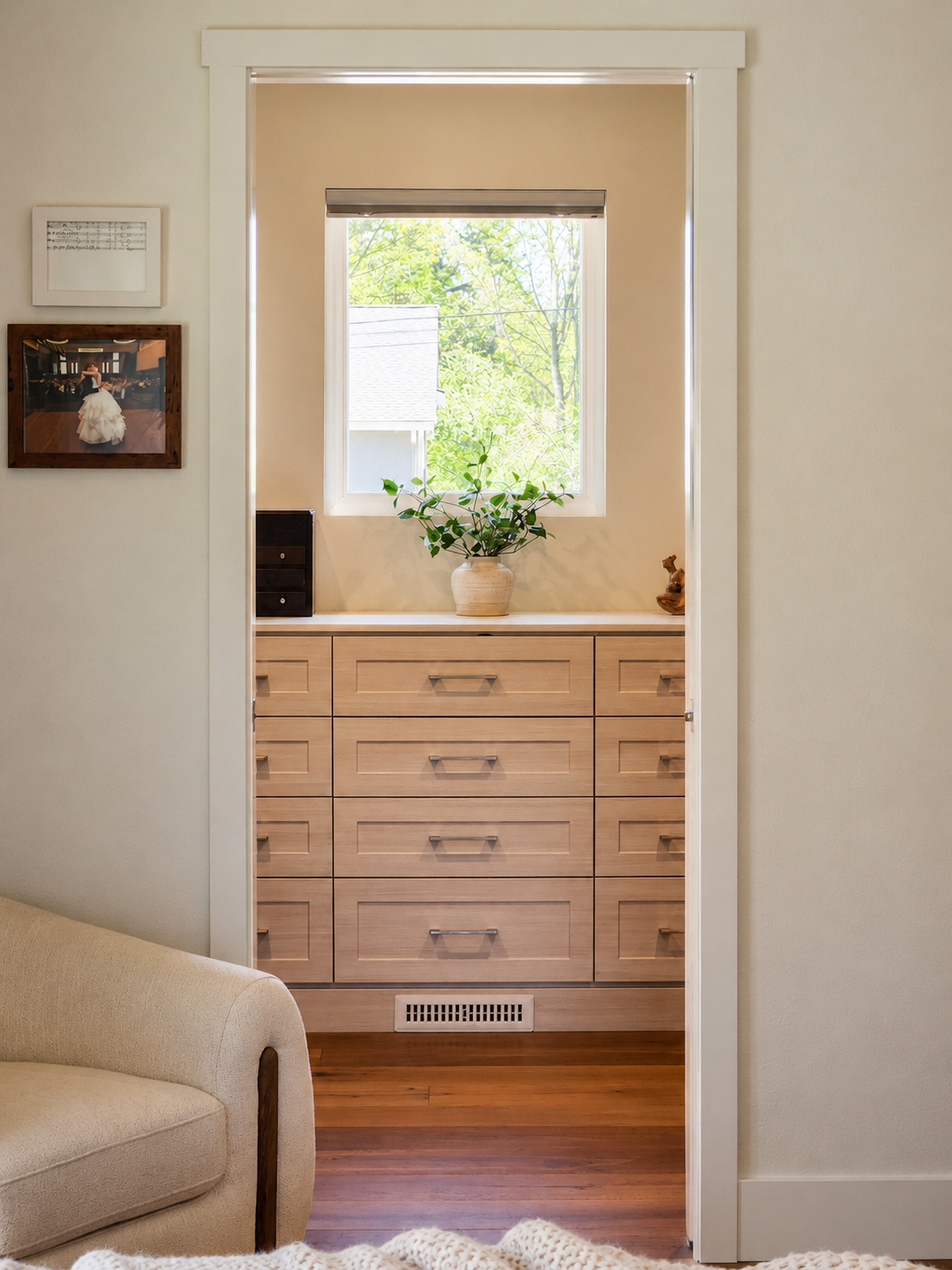 Primary closet with natural light from window, wood cabinetry and view to landscape.
