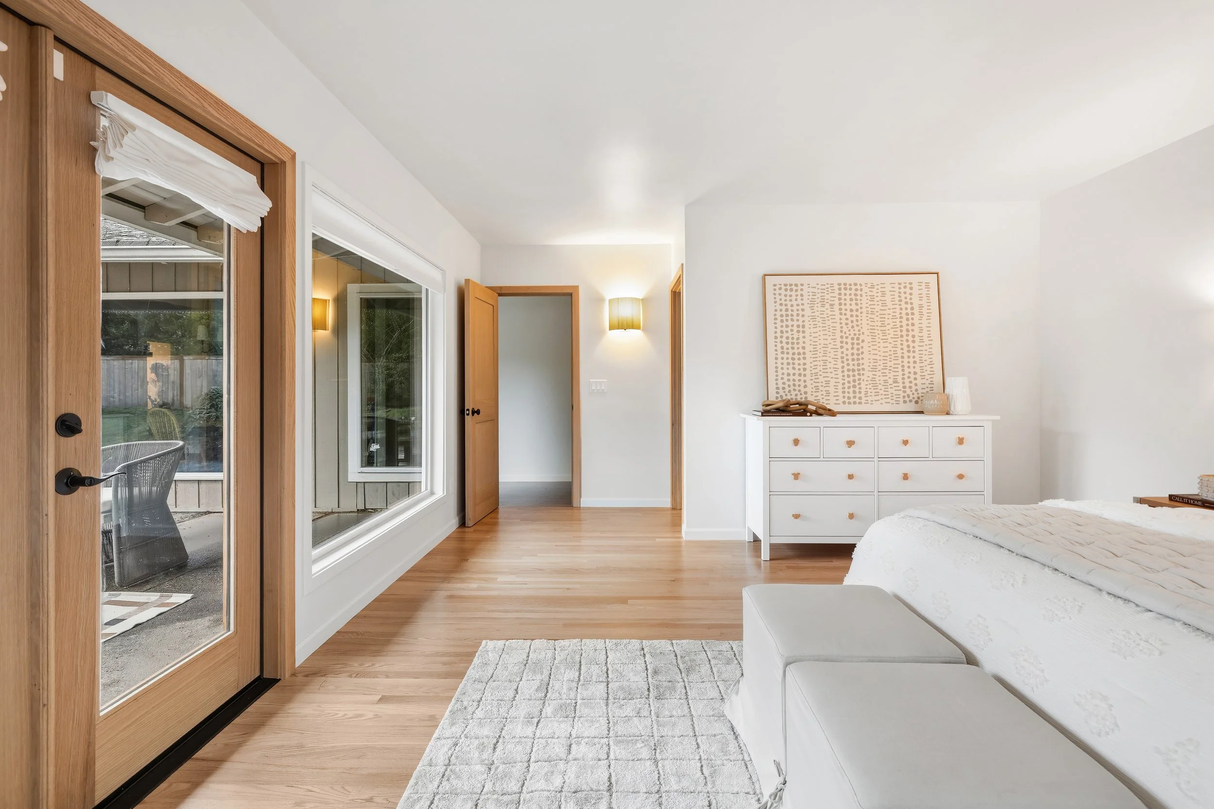 Guest bedroom with wood-framed french doors opening to outdoor space and minimalist furnishings.