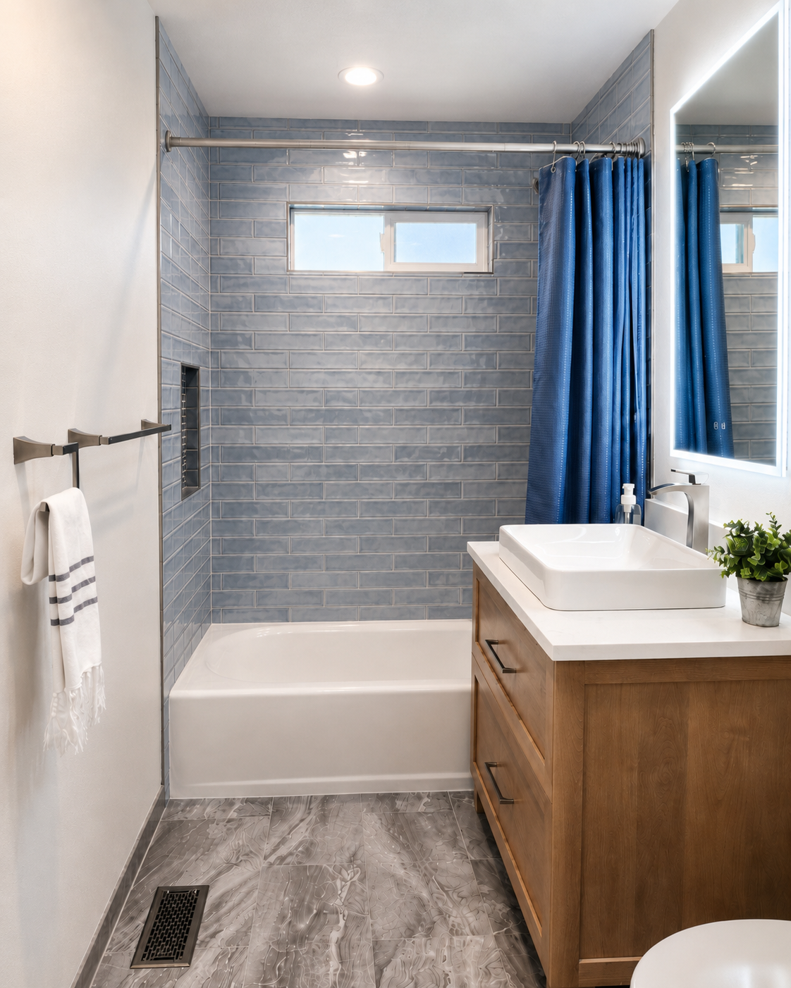Hall bathroom with blue subway tile in shower, wood vanity with white vessel sink and brushed nickel accents.