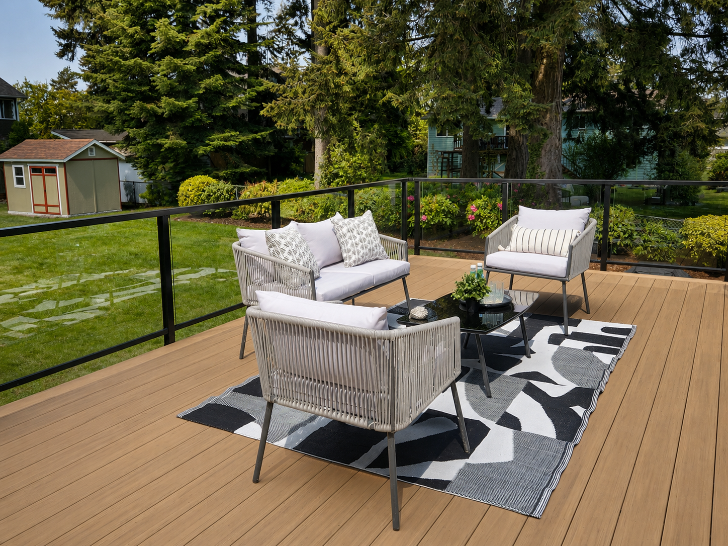 Expanded composite deck with glass panel railing seating and mature landscape surroundings.