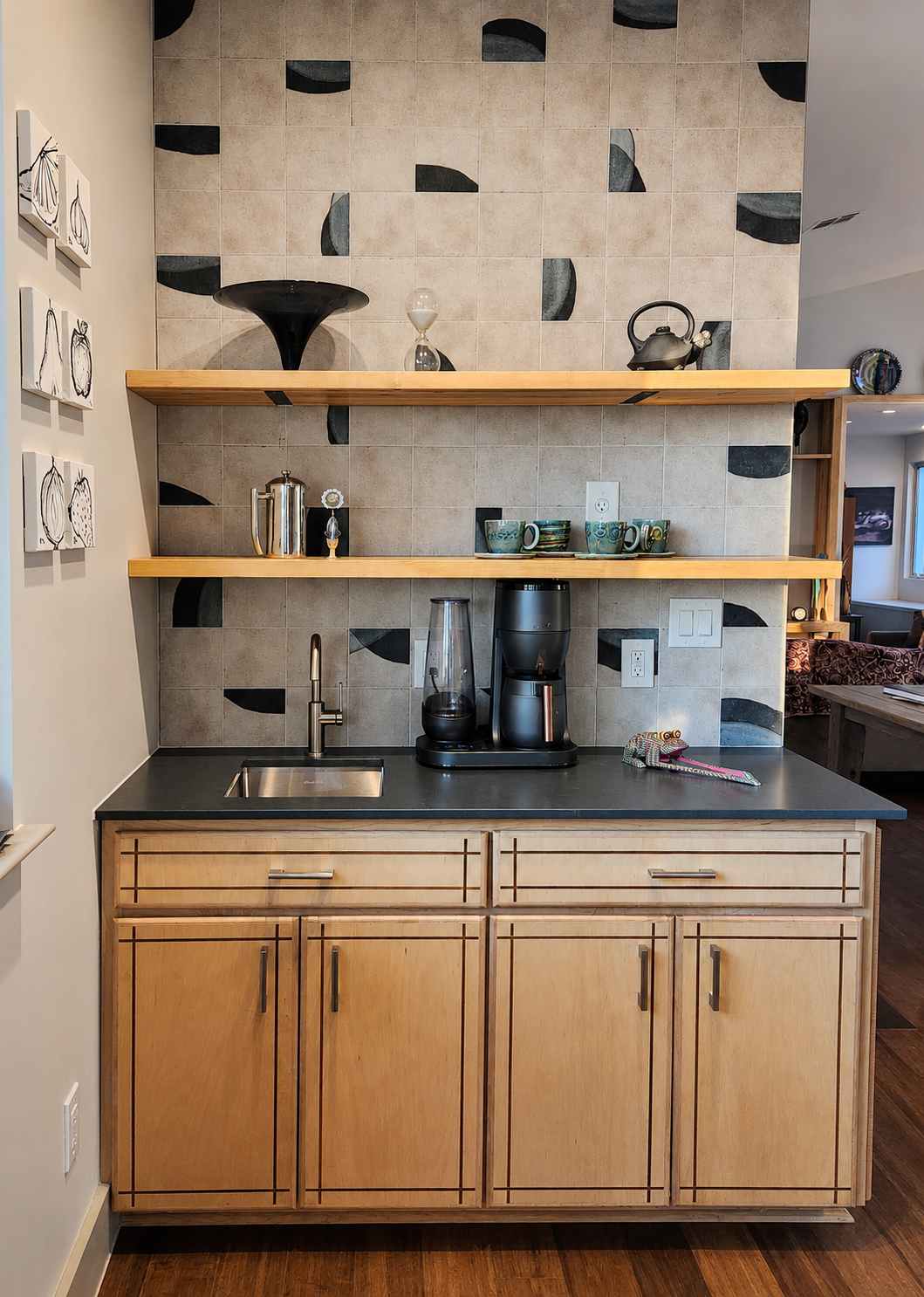 Coffee station with layered finishes—wood cabinetry, patterned tile, and open shelving displaying coffee equipment and decor.