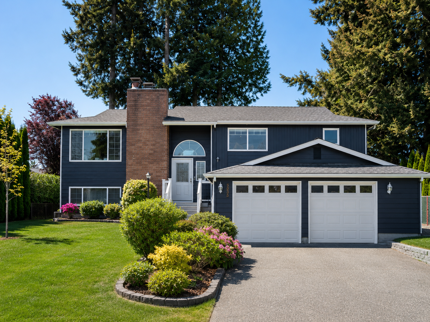 Home exterior with dark blue siding and white trim, orange brick chimney, and mature landscaping.
