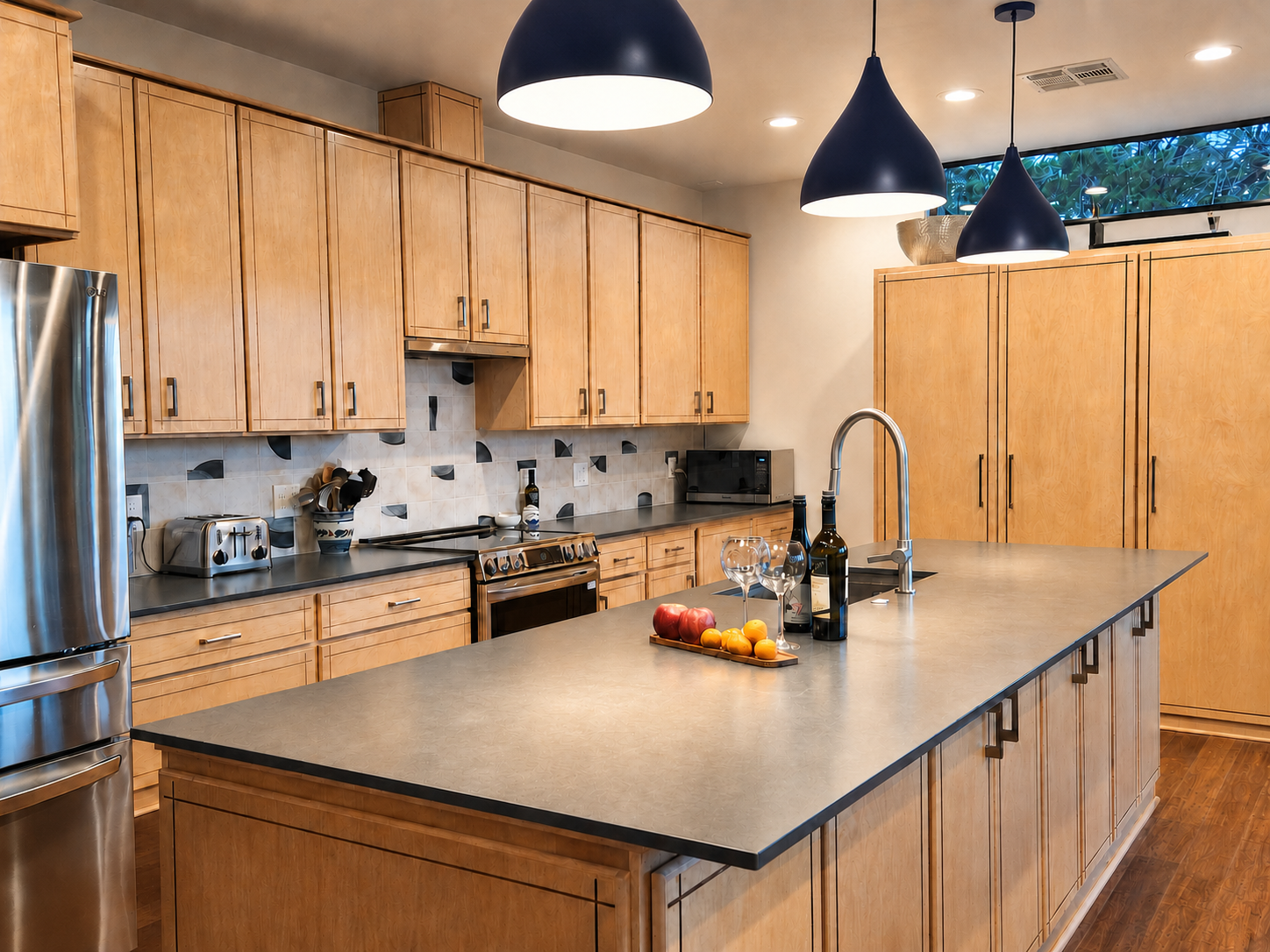 Contemporary kitchen with custom wood cabinetry, patterned tile backsplash, and layered finishes in warm and cool tones.