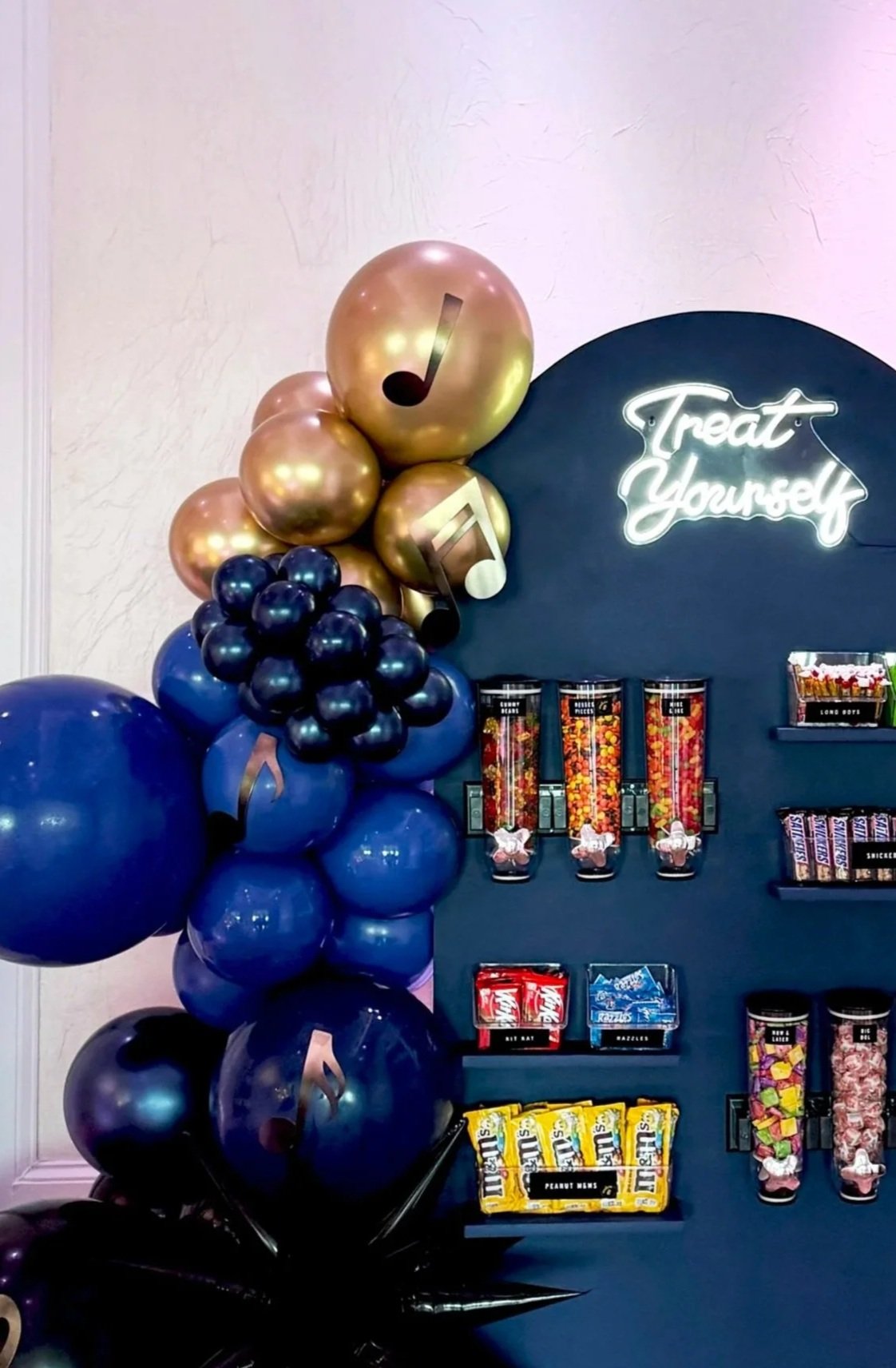 Colorful balloons and a snack display with a neon sign that says 'Treat Yourself'