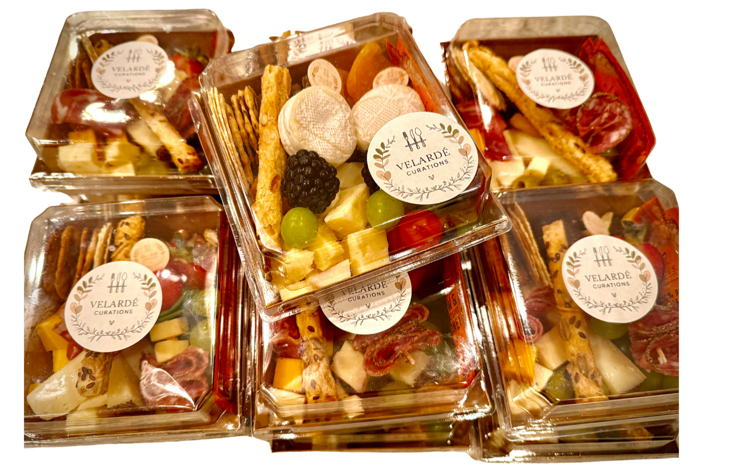 Charcuterie boxes filled with assorted cheese and meat snacks, labeled 'Velarde Curations,' stacked together.