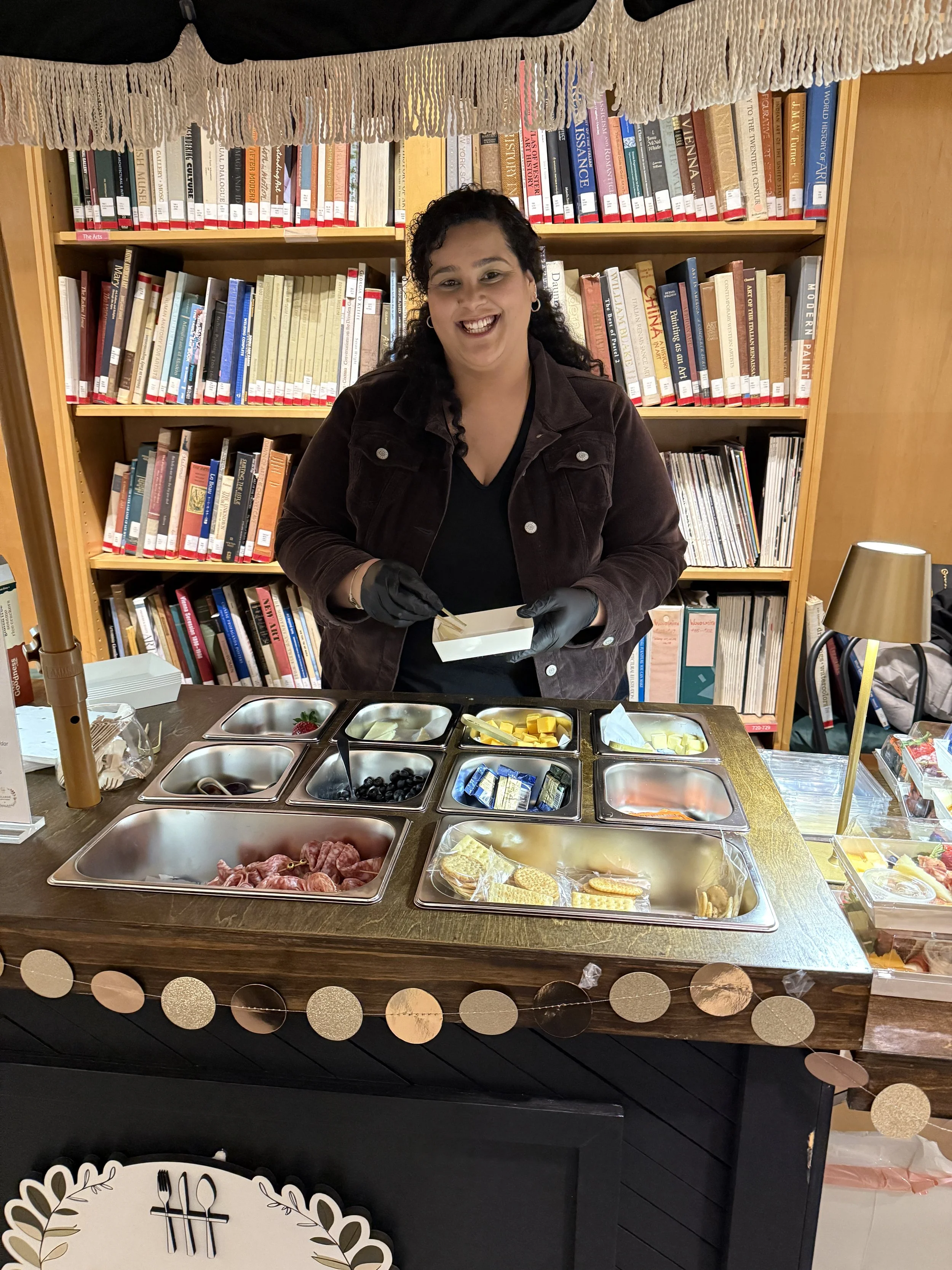 Woman serving herself food at a buffet with a bookshelf in the background.