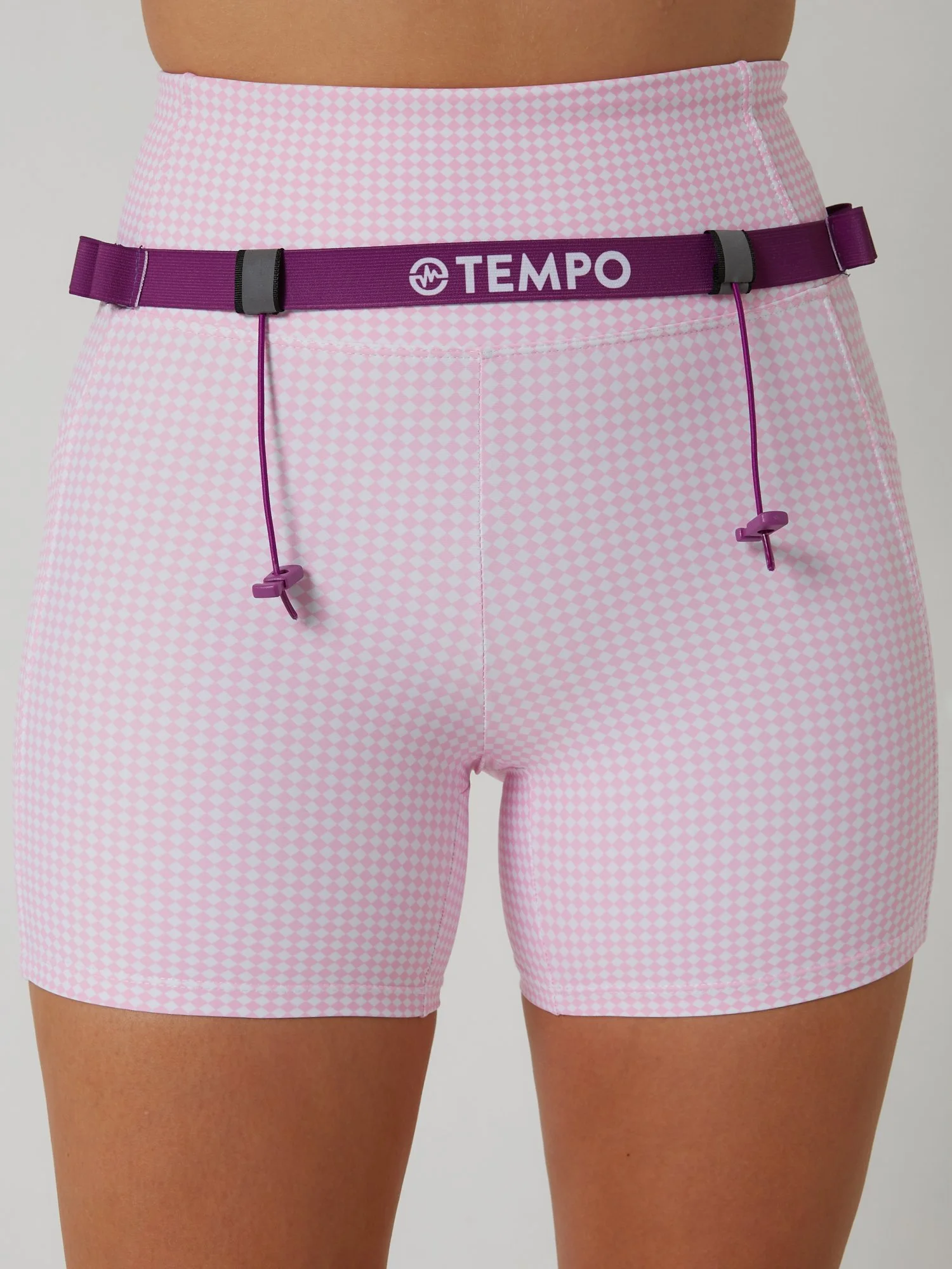 Runner wearing the PACE / VIOLET purple race belt with race bib and energy gels secured for race day running.