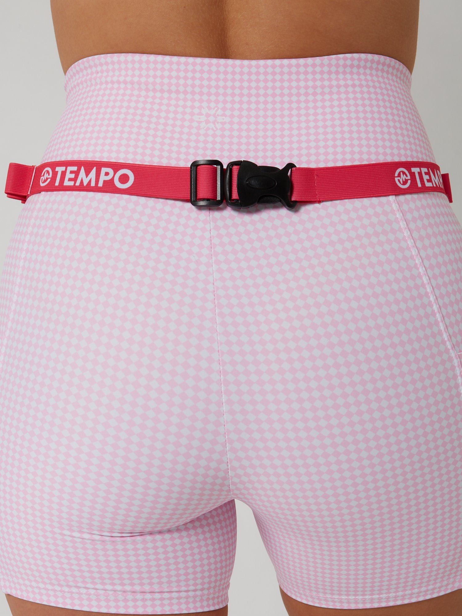 Runner wearing the PACE / ROSE pink race belt with race bib and energy gels secured for race day running.