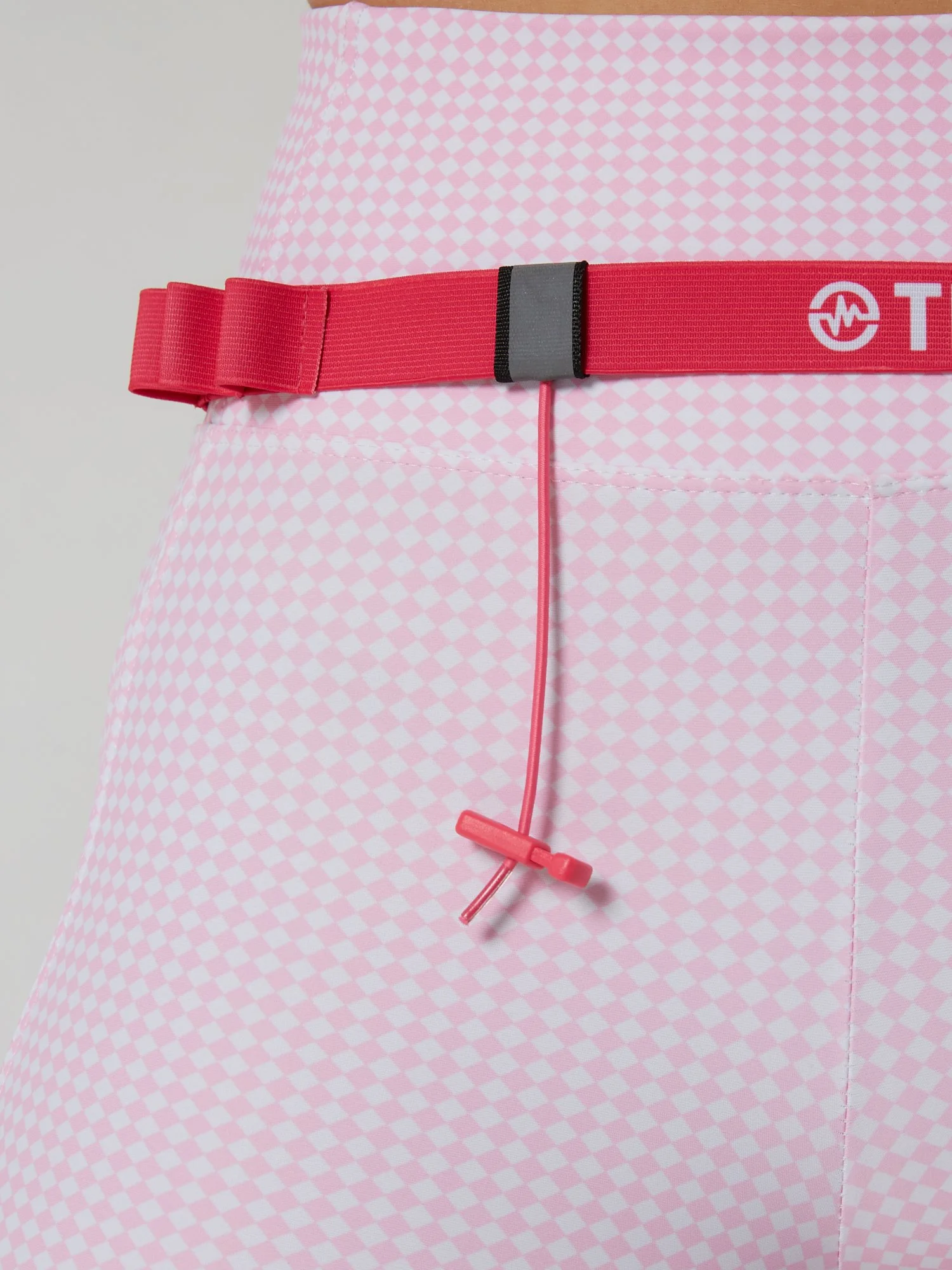 Runner wearing the PACE / ROSE pink race belt with race bib and energy gels secured for race day running.