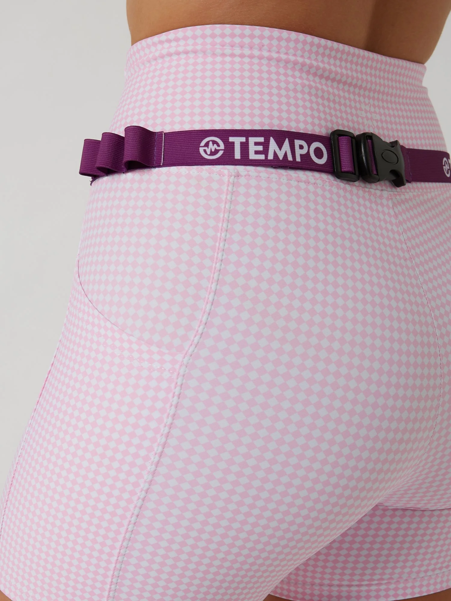 Runner wearing the PACE / VIOLET purple race belt with race bib and energy gels secured for race day running.