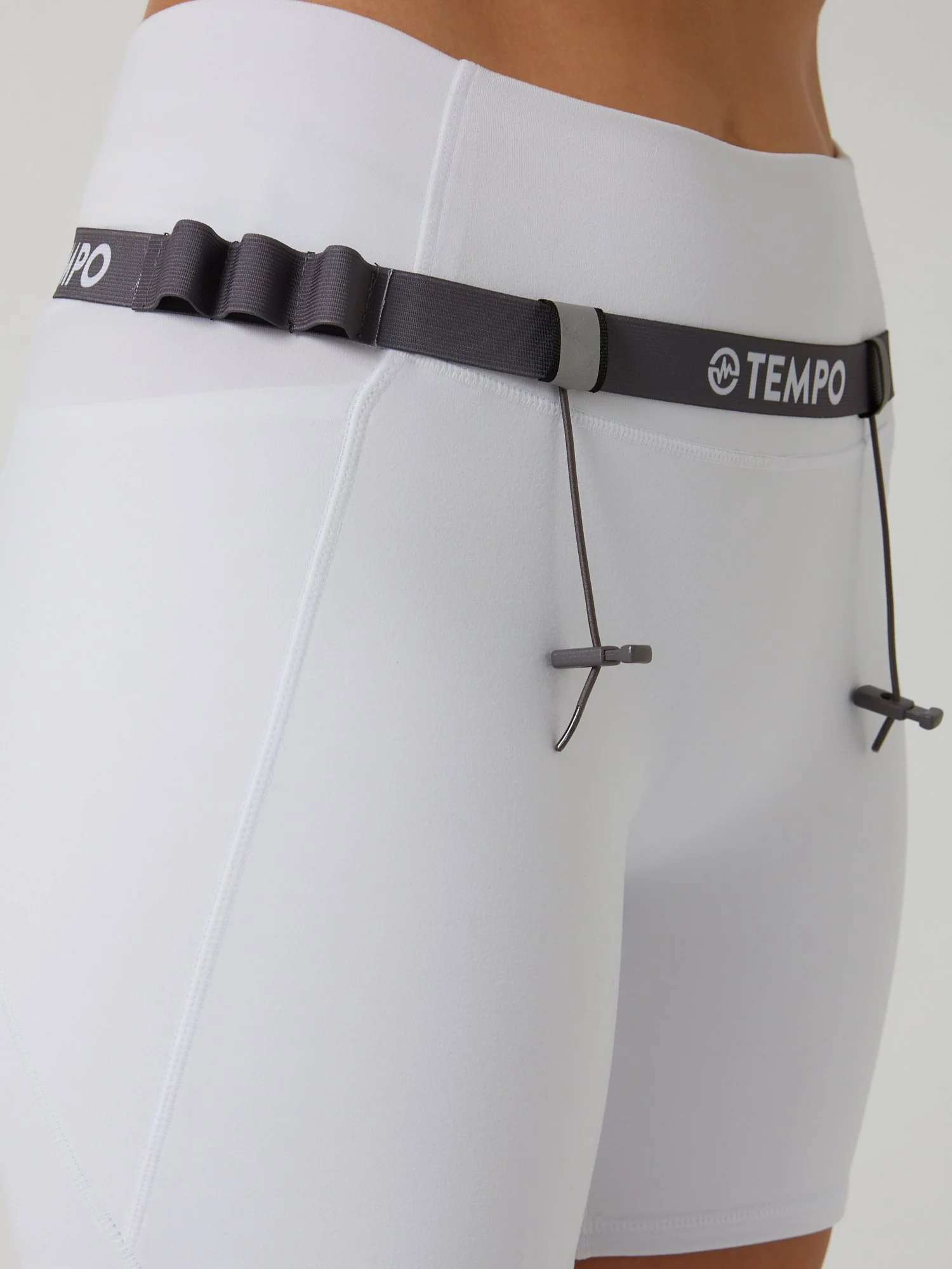 Runner wearing the PACE / ASH grey race belt with race bib and energy gels secured for race day running.