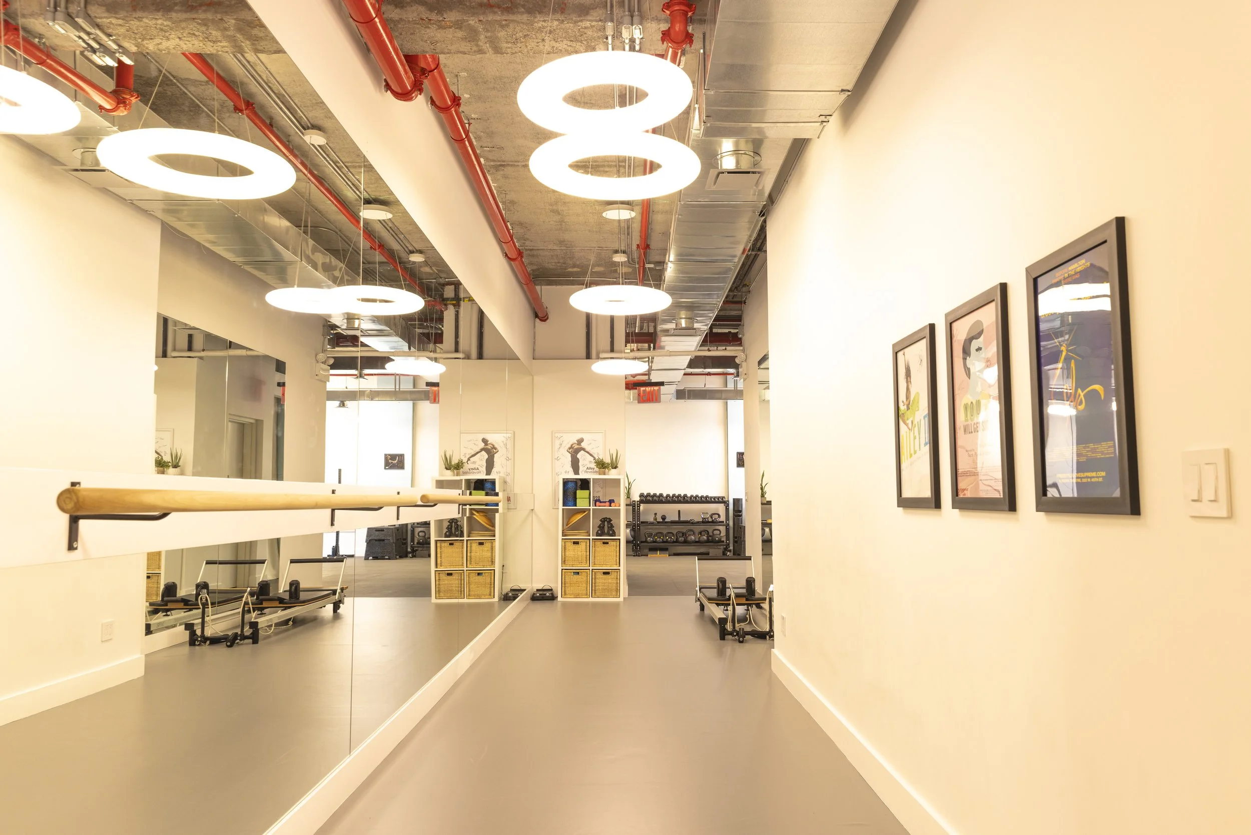 Photo of an interior fitness studio with exercise equipment, wall art, and mirrored wall.