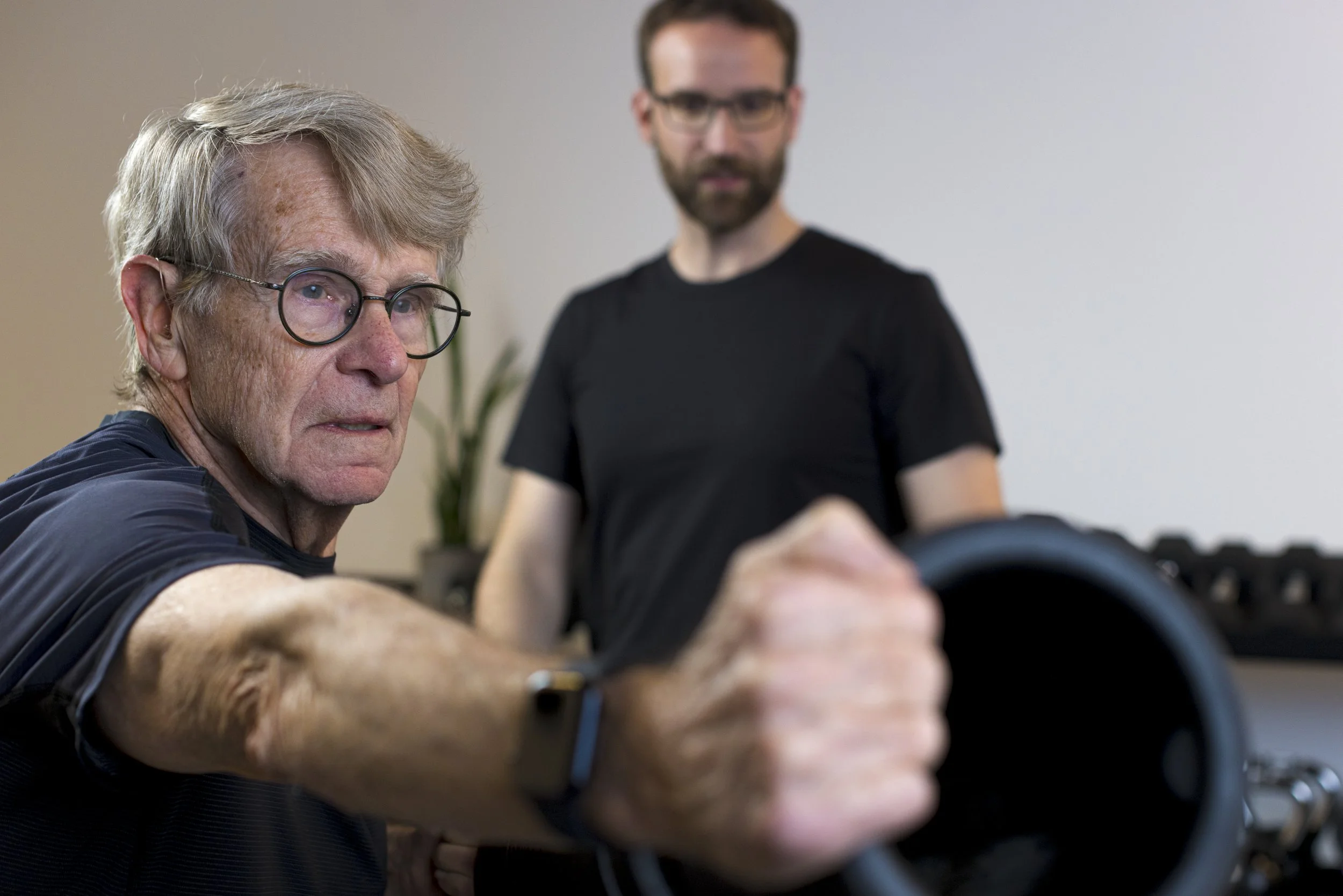 Man lifting at a gym with personal trainer coaching strength and conditioning at FlySpace Physical Therapy in New York.