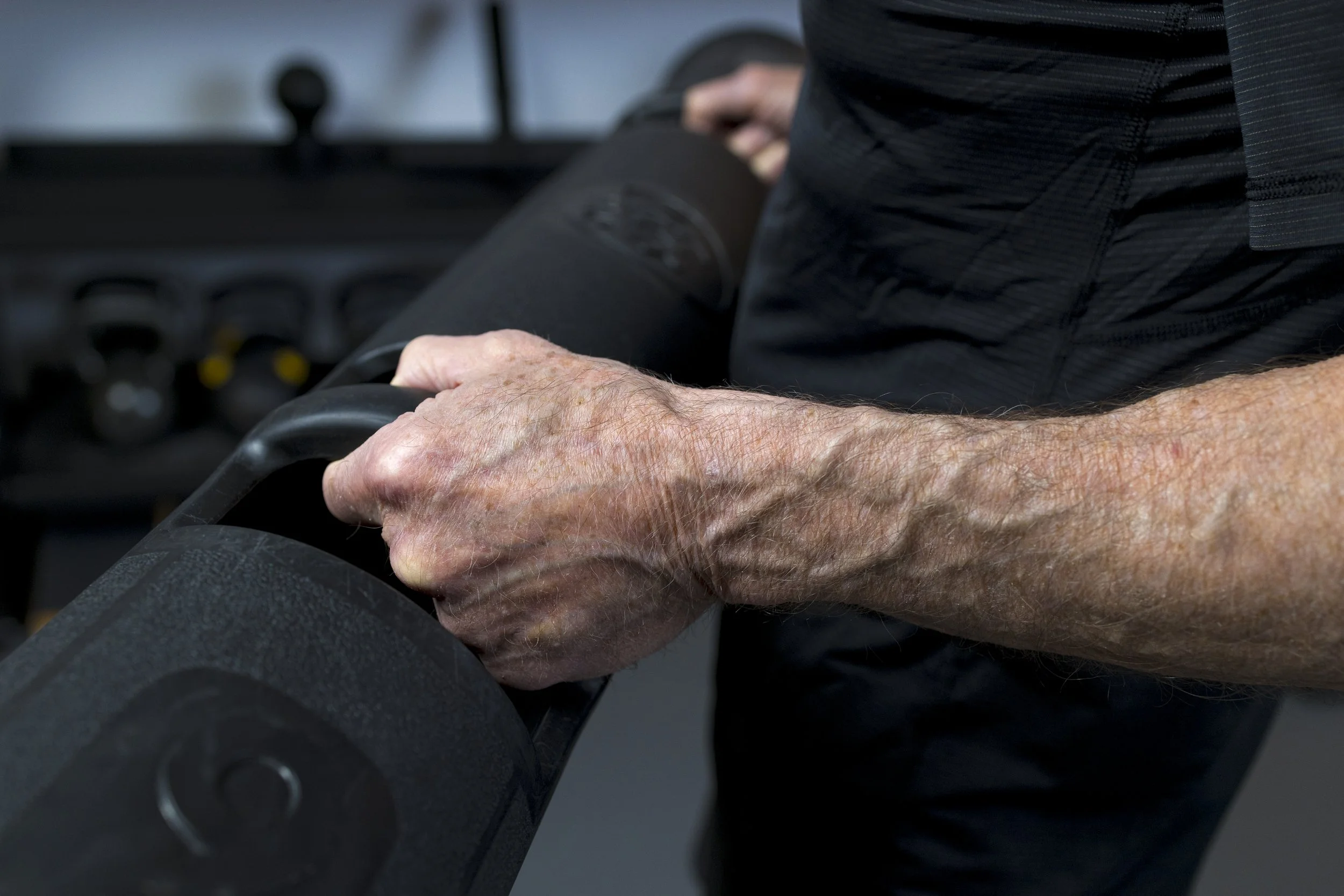 A person gripping a weightlifting barbell at FlySpace Physical Therapy in New York.