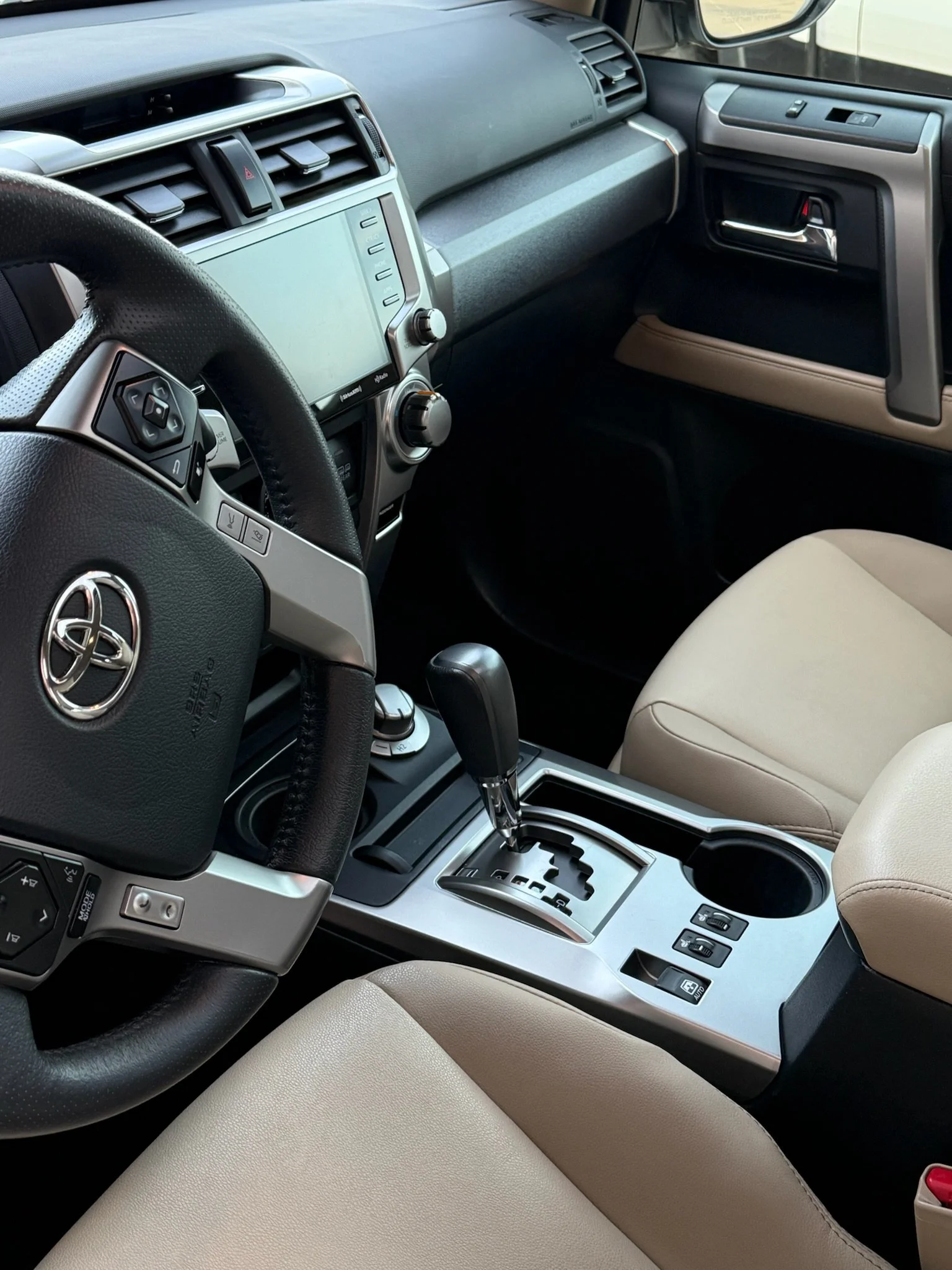 Interior of a Toyota vehicle showing the steering wheel, dashboard, gear shift, and front passenger seat.