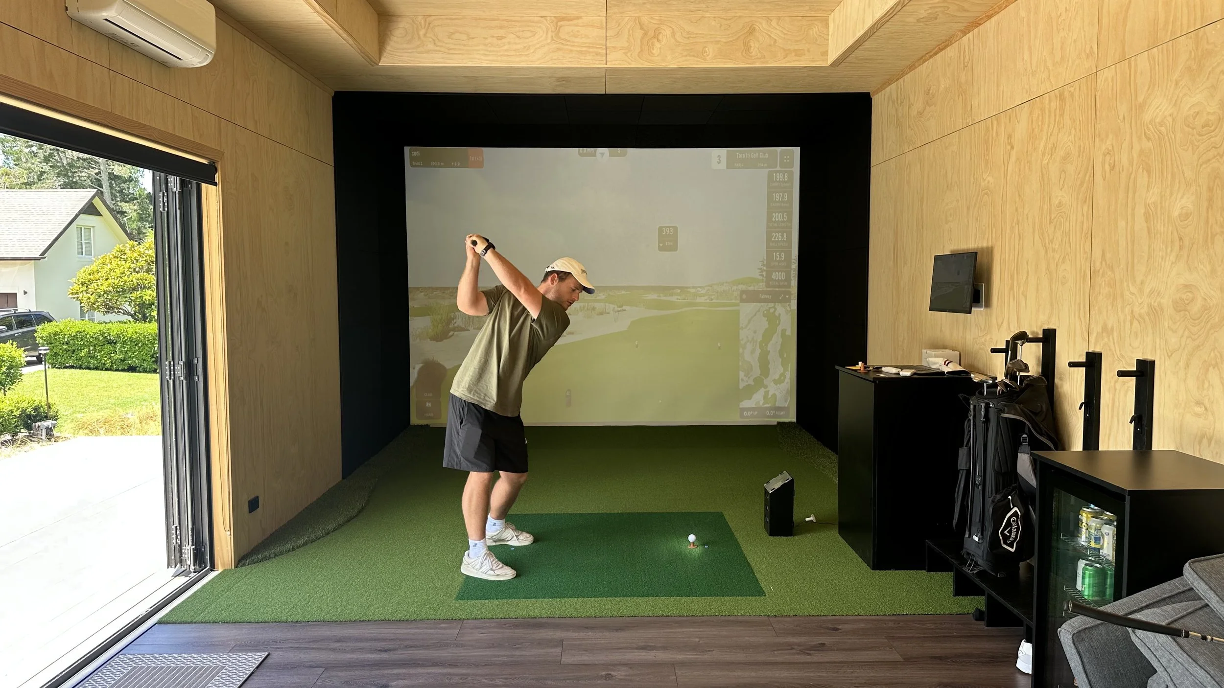 Codi, owner of Greyson Builders playing golf in golf simulator built by Greyson Builders in Coatesville, Auckland