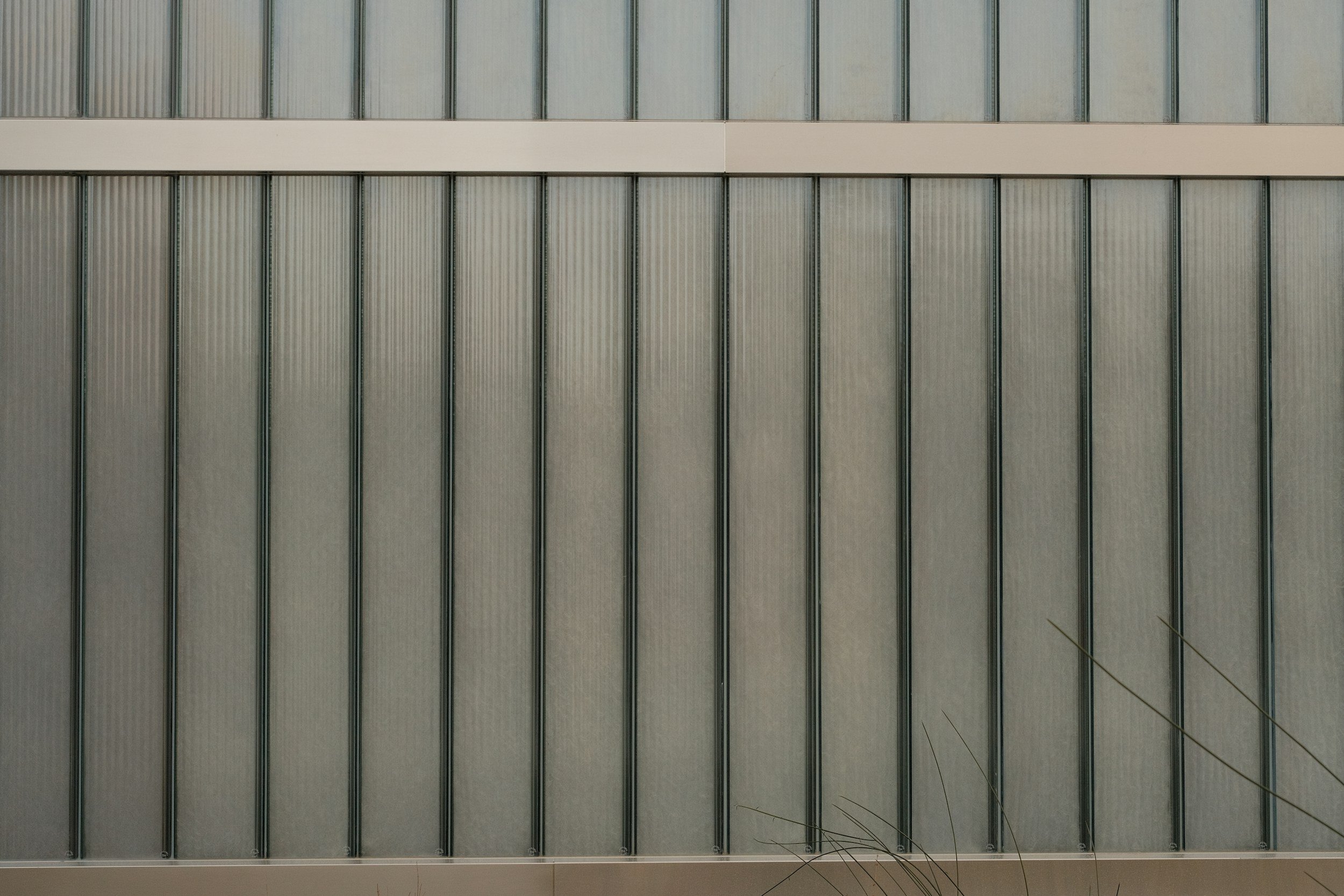 Close-up of a modern building's exterior wall with vertical metal panels and horizontal beams showing the architectural design.