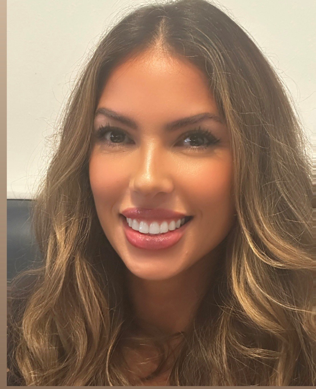 A woman with long wavy hair smiling at the camera.