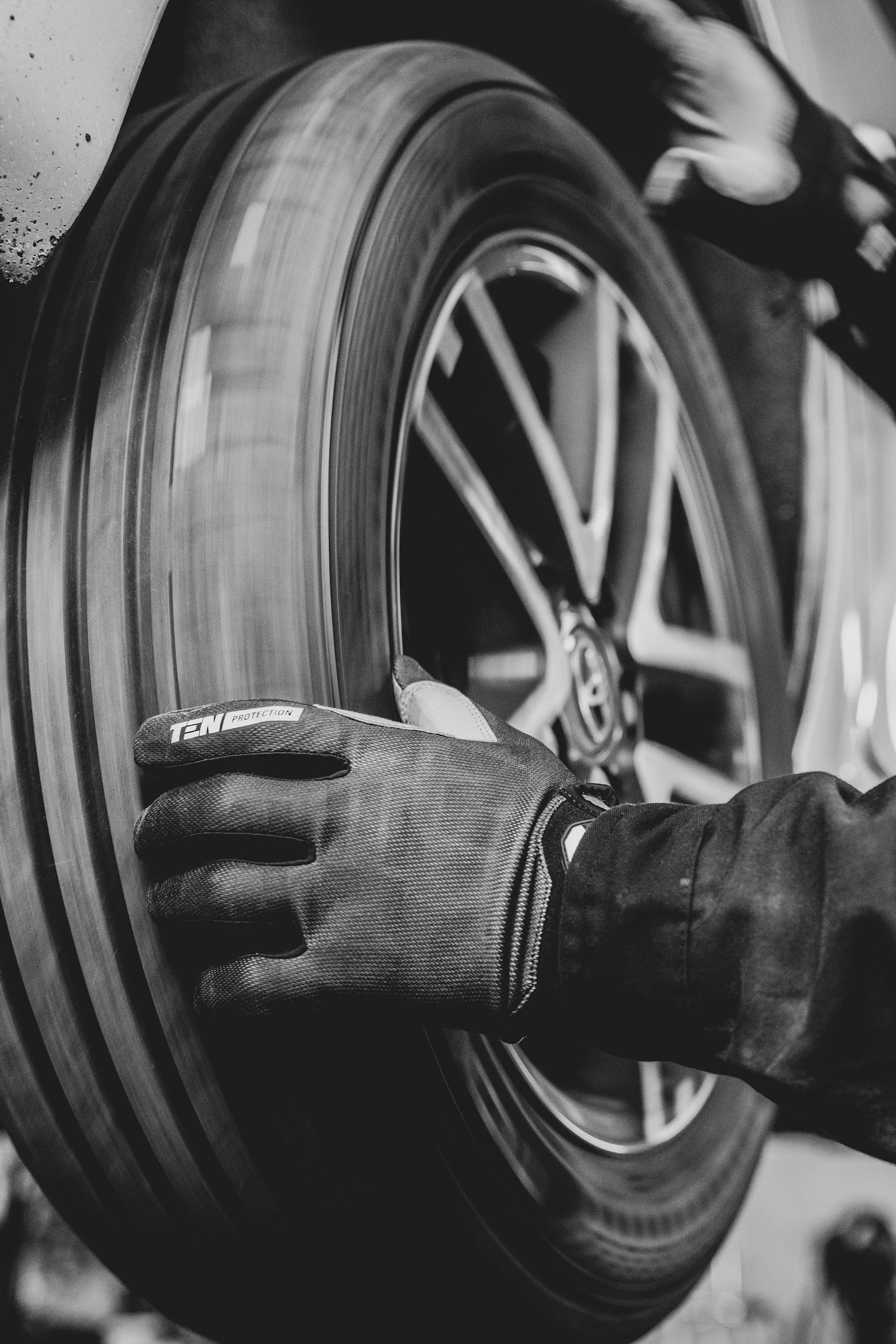 A person wearing a glove is installing or inspecting a car tire with a Volkswagen logo on the wheel rim.