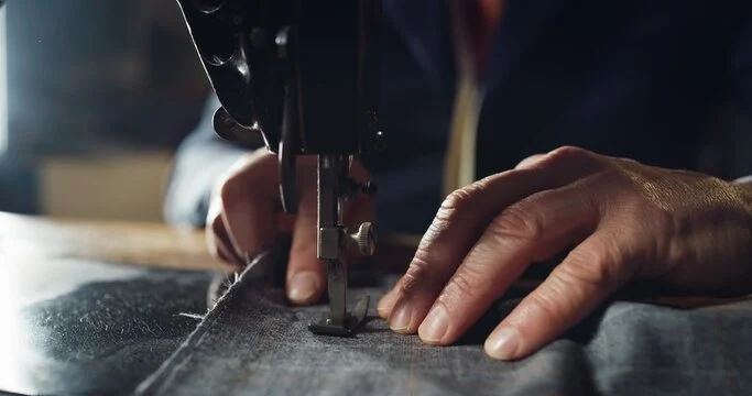 Close-up of hands guiding fabric through a sewing machine.