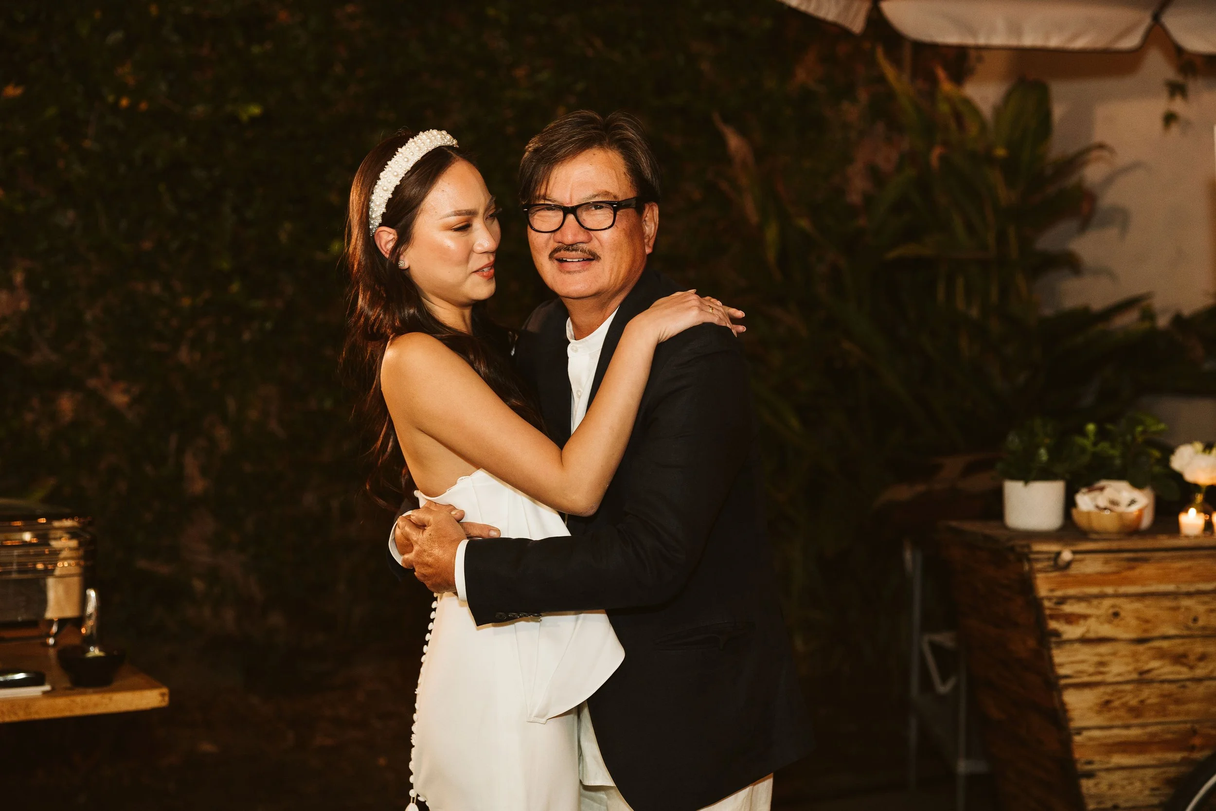 Bride dancing with a smiling man in glasses during the wedding reception.