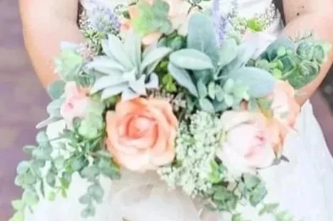 Woman holding a bouquet of pink roses, succulents, and greenery.
