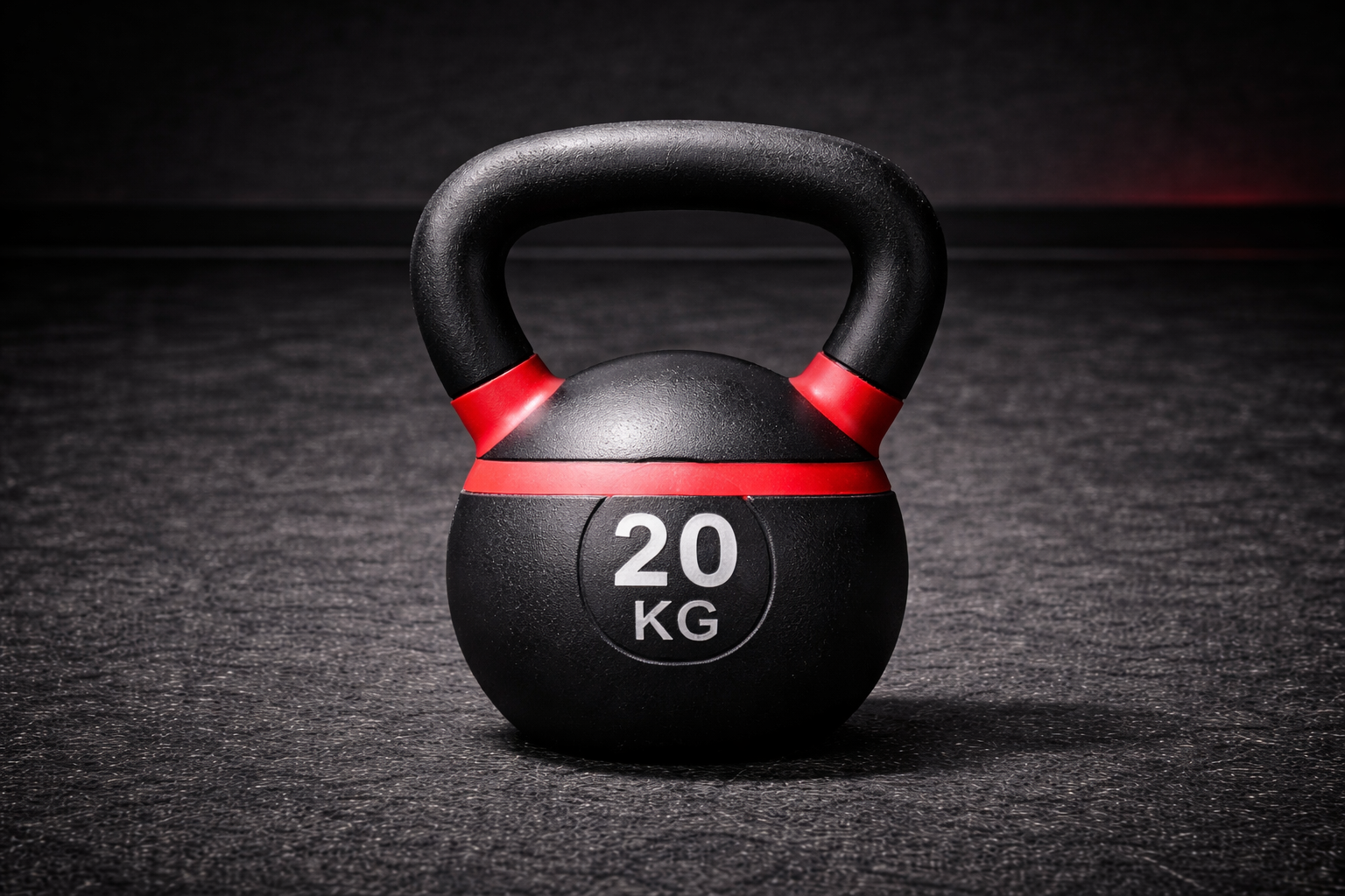 A black kettlebell with red accents on a textured black surface, marked with '20 KG' in white, isolated against a dark background.