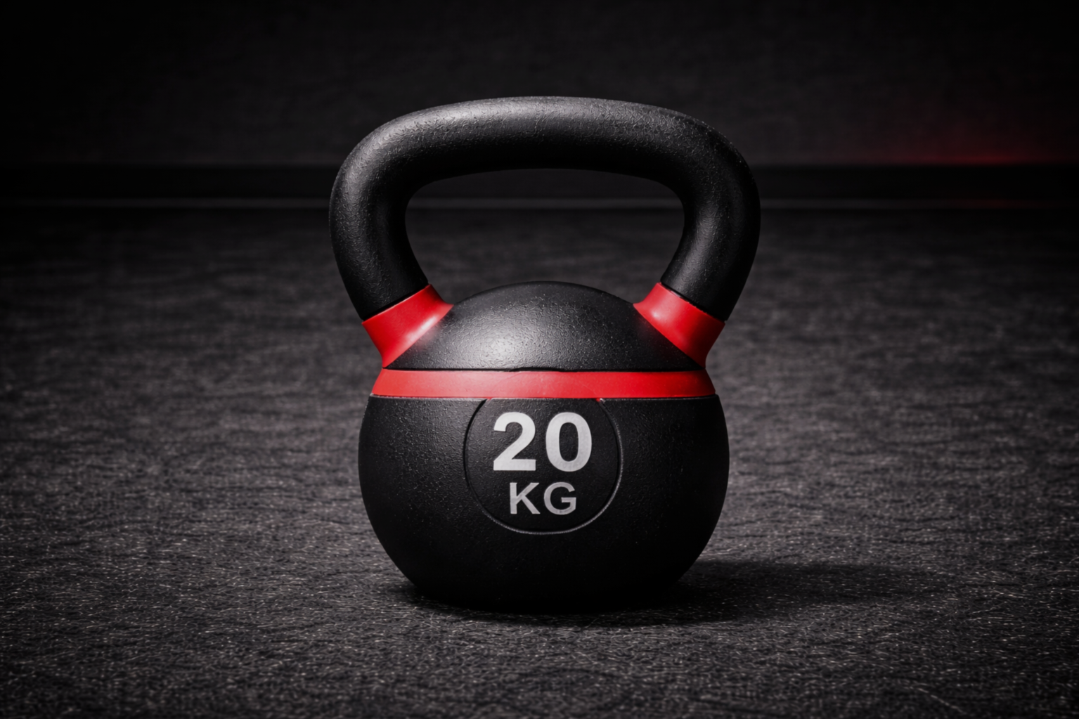 A black kettlebell with red accents, marked 20 kg, placed on a black textured surface.
