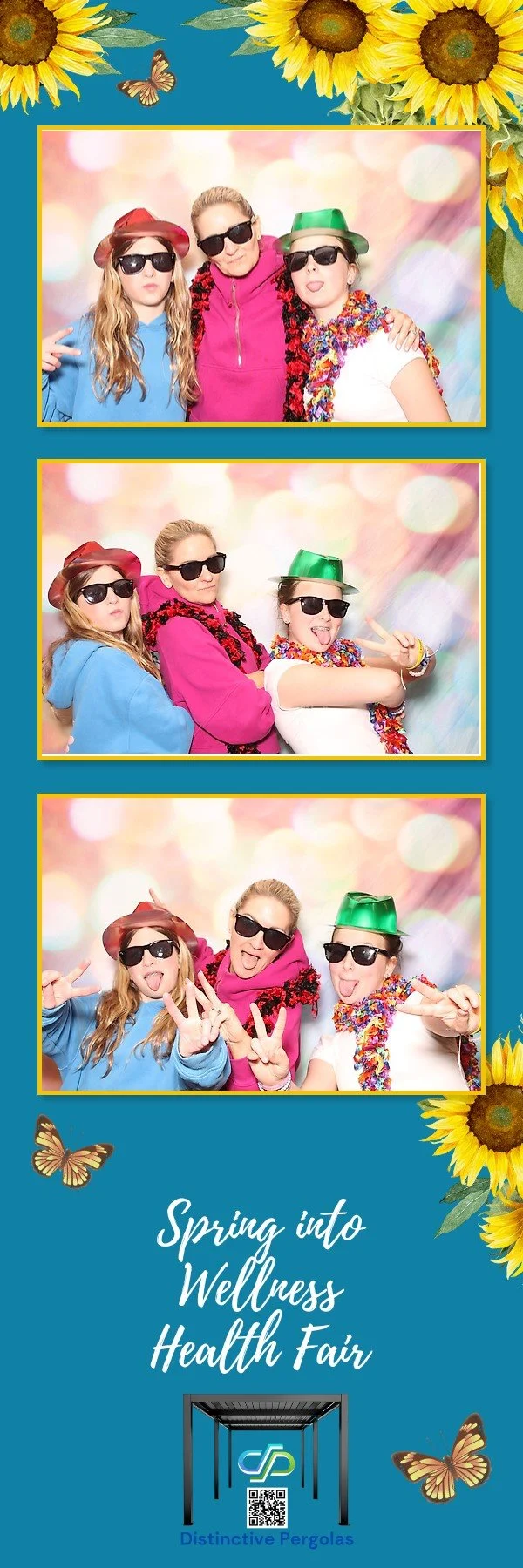 Three women wearing sunglasses, colorful leis, and hats posing in a photo booth with a pink and pastel background, at the Spring into Wellness Health Fair, decorated with sunflower and butterfly graphics.