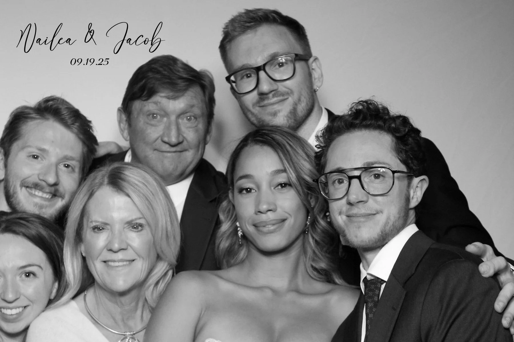 A group of eight people in black and white, dressed formally, posing for a photo. Text in the upper left corner reads 'Nailea & Jacob 09.19.25'.
