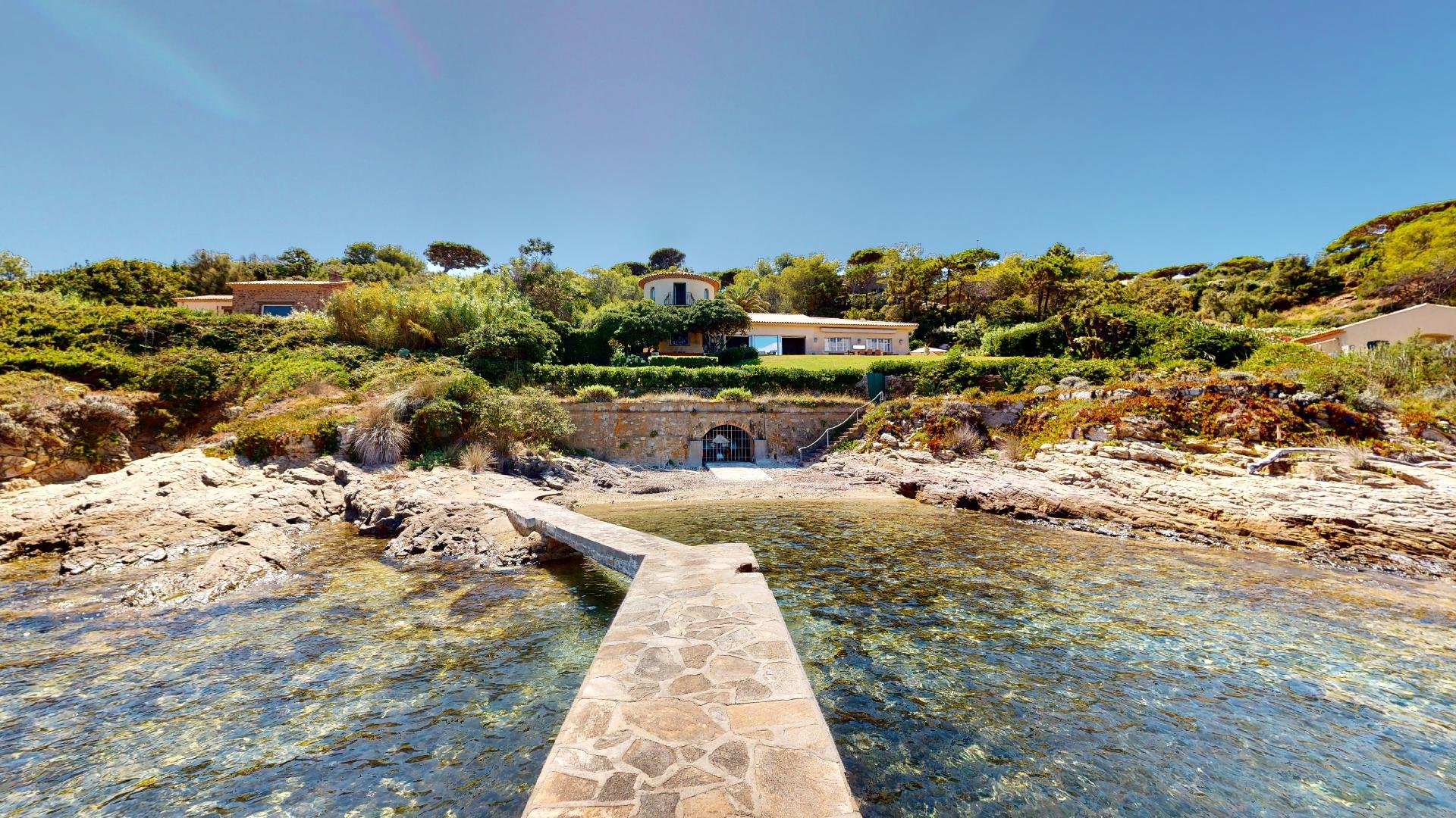 Stone pathway leading to the beach in Les Parcs de Saint-Tropez with clear Mediterranean water.