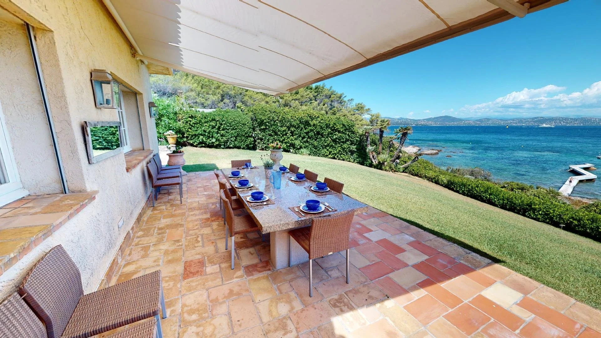 Outdoor dining terrace overlooking the sea at waterfront villa in Saint-Tropez.